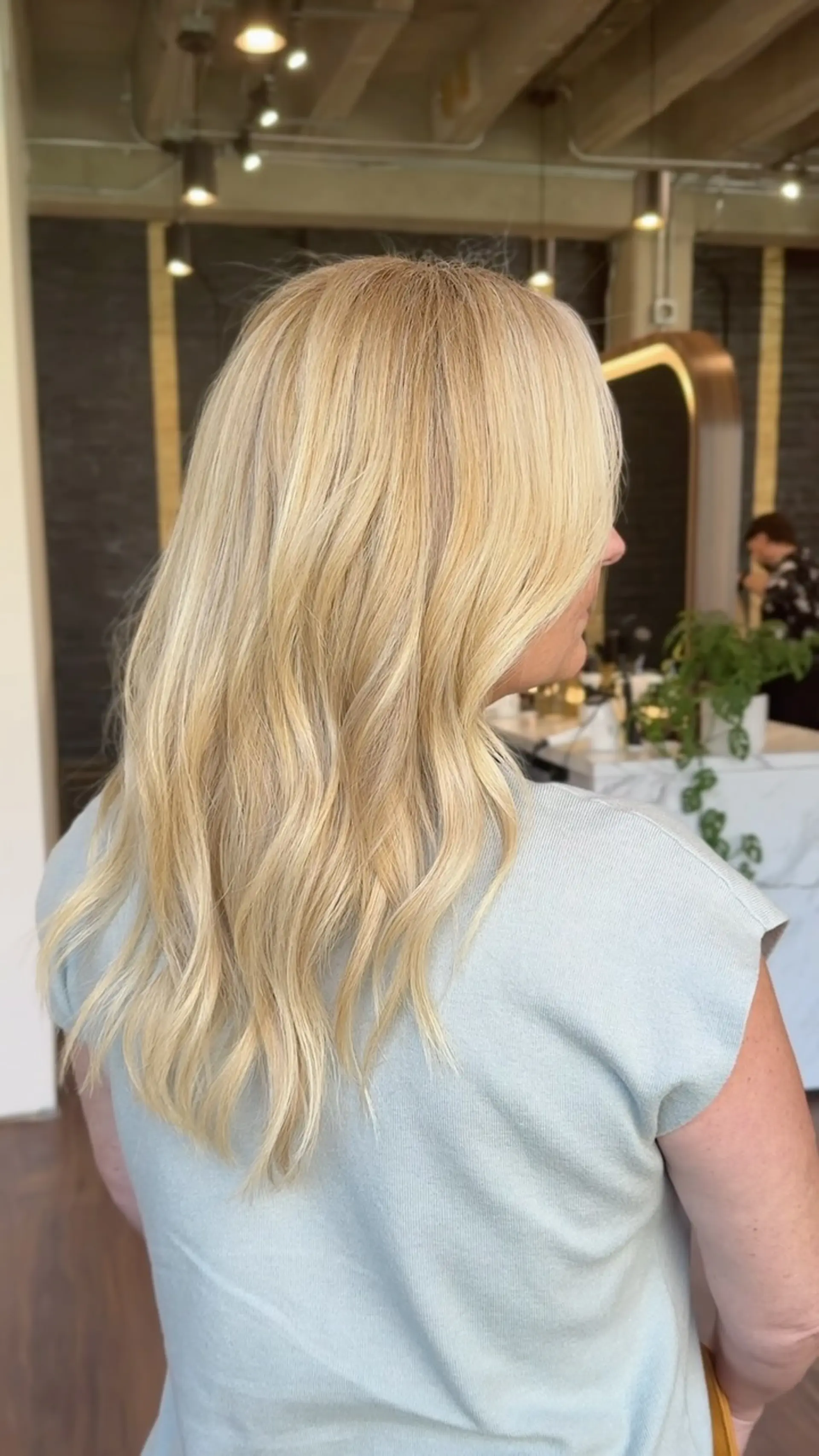 Bright dimensional blonde balayage styled in loose, soft waves cascading down the back. 1