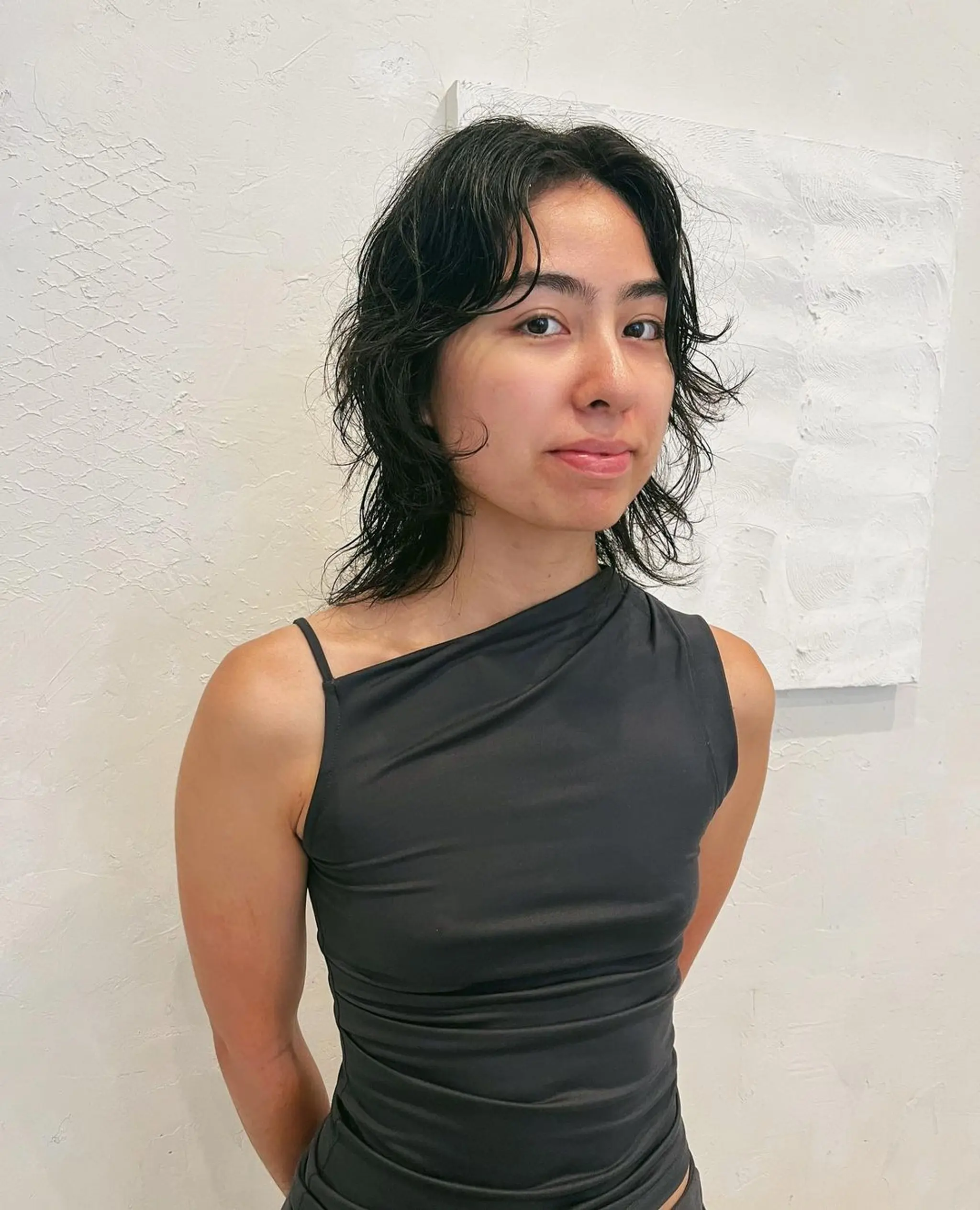 Medium-length black hair styled in a shag cut with wavy layers for a natural, slightly messy look. 2
