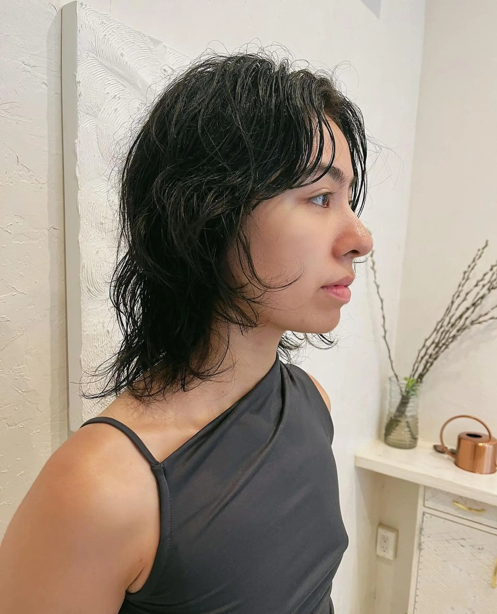 Medium-length black hair styled in a shag cut with wavy layers for a natural, slightly messy look. 1