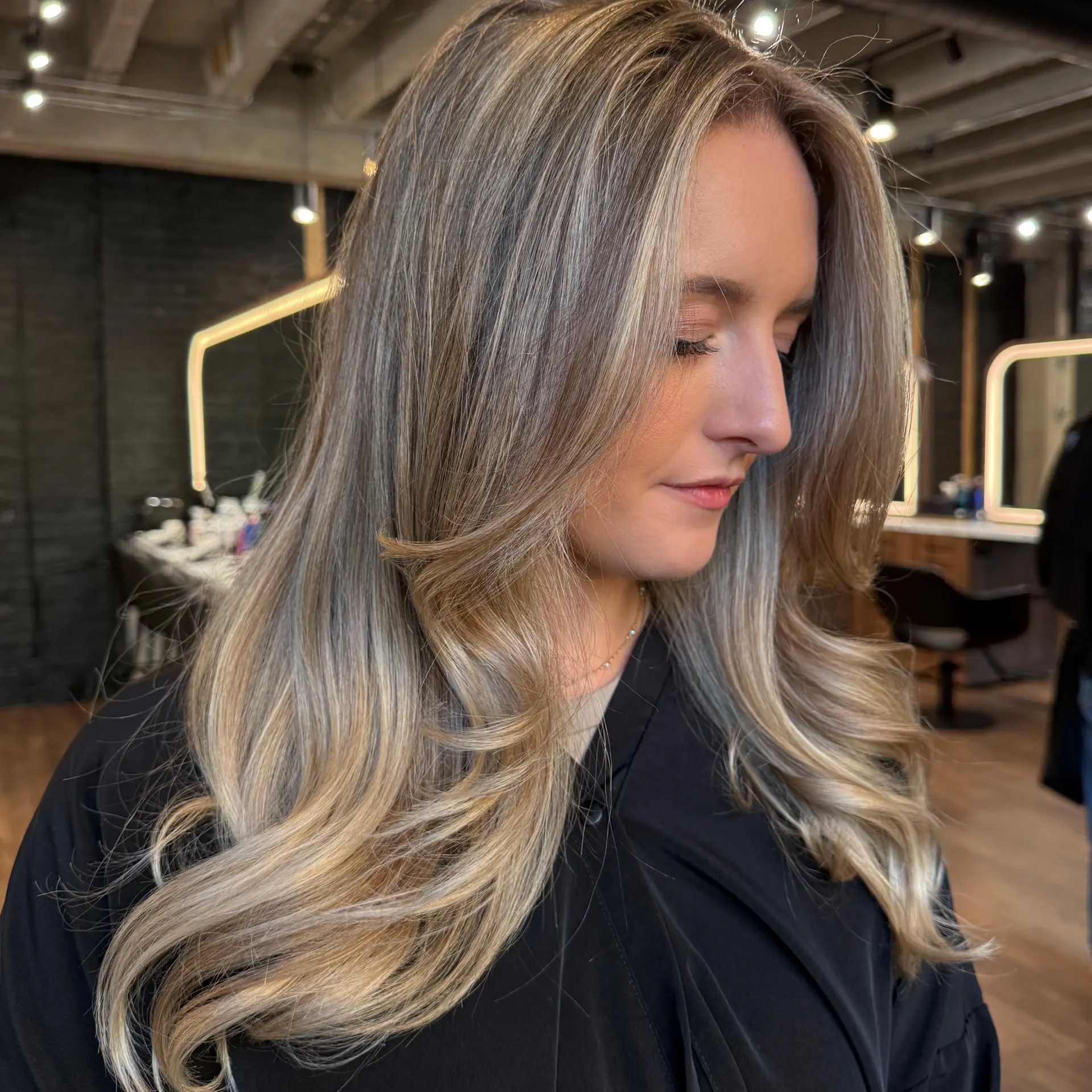 Long layered dimensional blonde hair styled into a voluminous blowout with soft flipped ends. 1