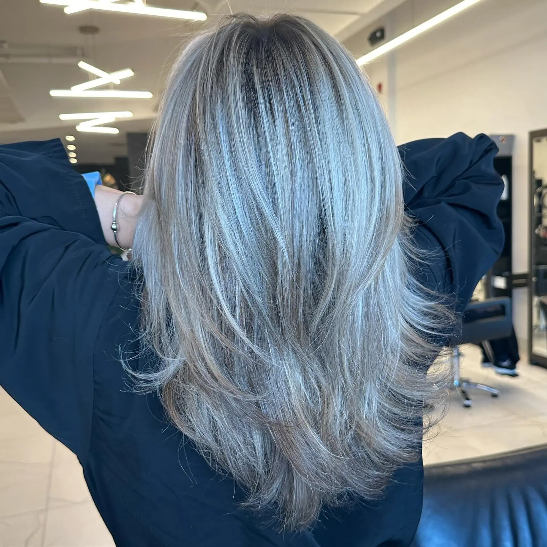 Cascading long layers featuring dimensional cool ash blonde highlights with soft feathered ends. 1