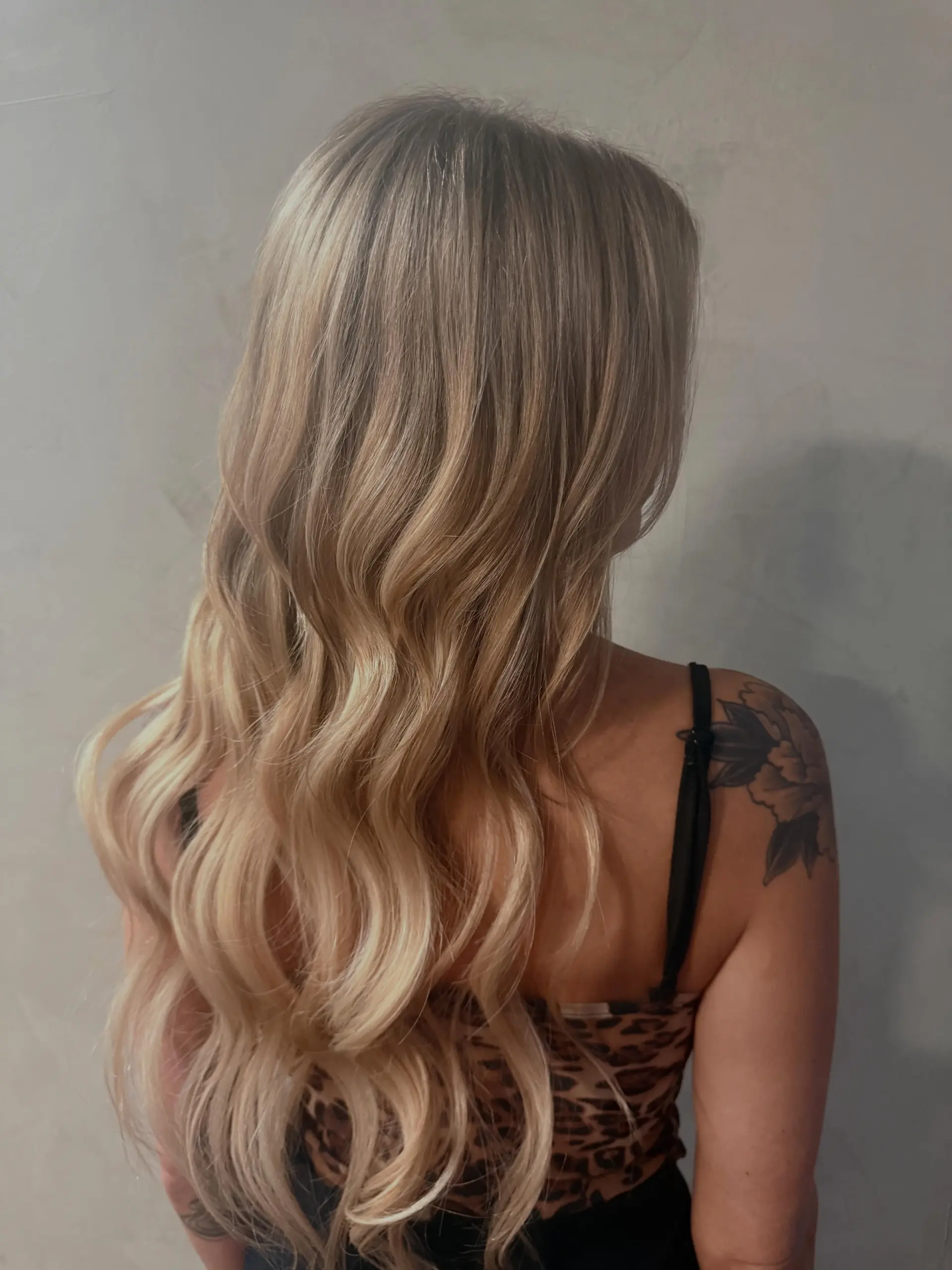 Long, multi-tonal blonde hair styled into soft flowing waves. 1