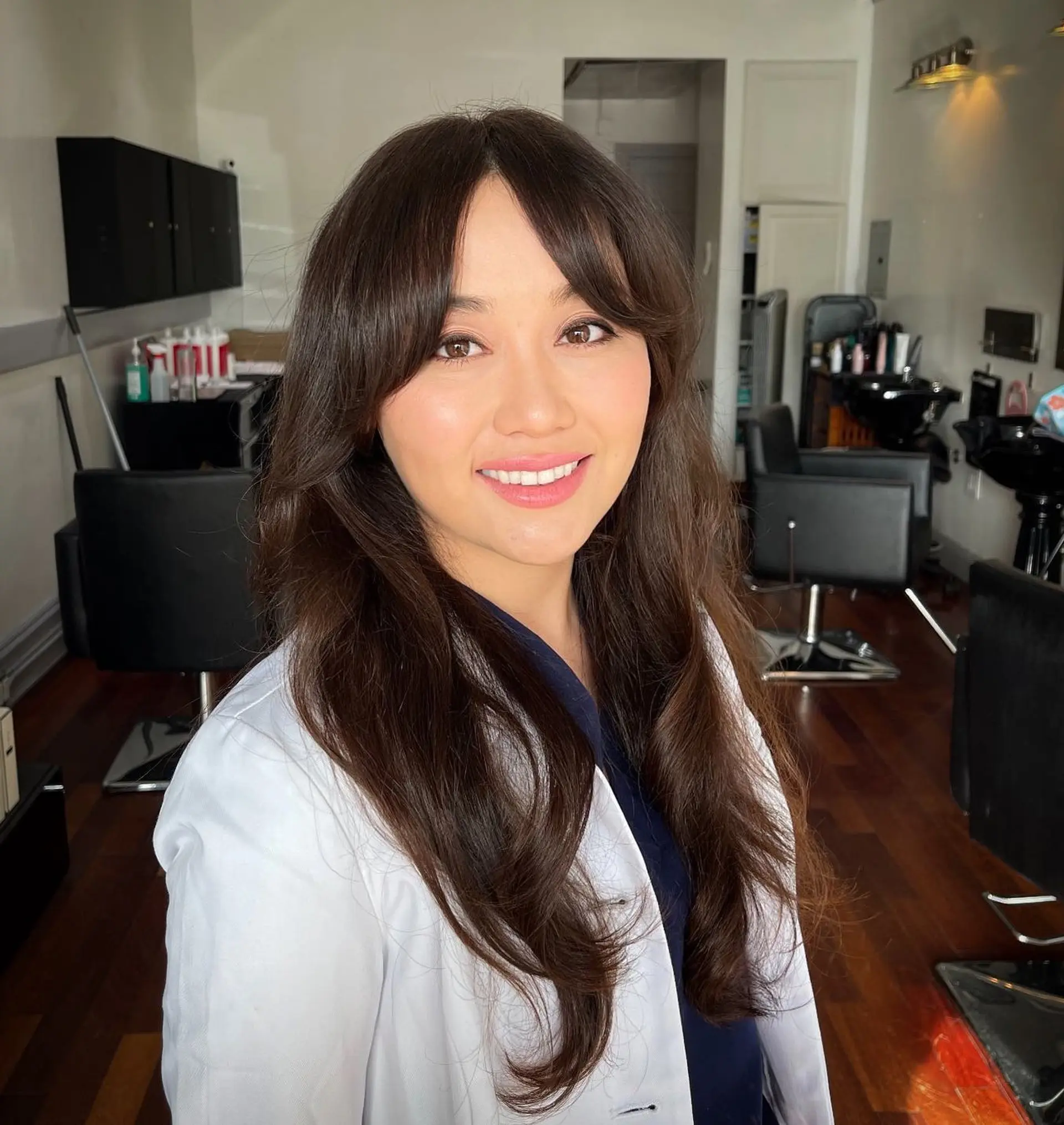 Long brunette hair styled in a full, polished blowout with flipped ends and soft curtain bangs. 1
