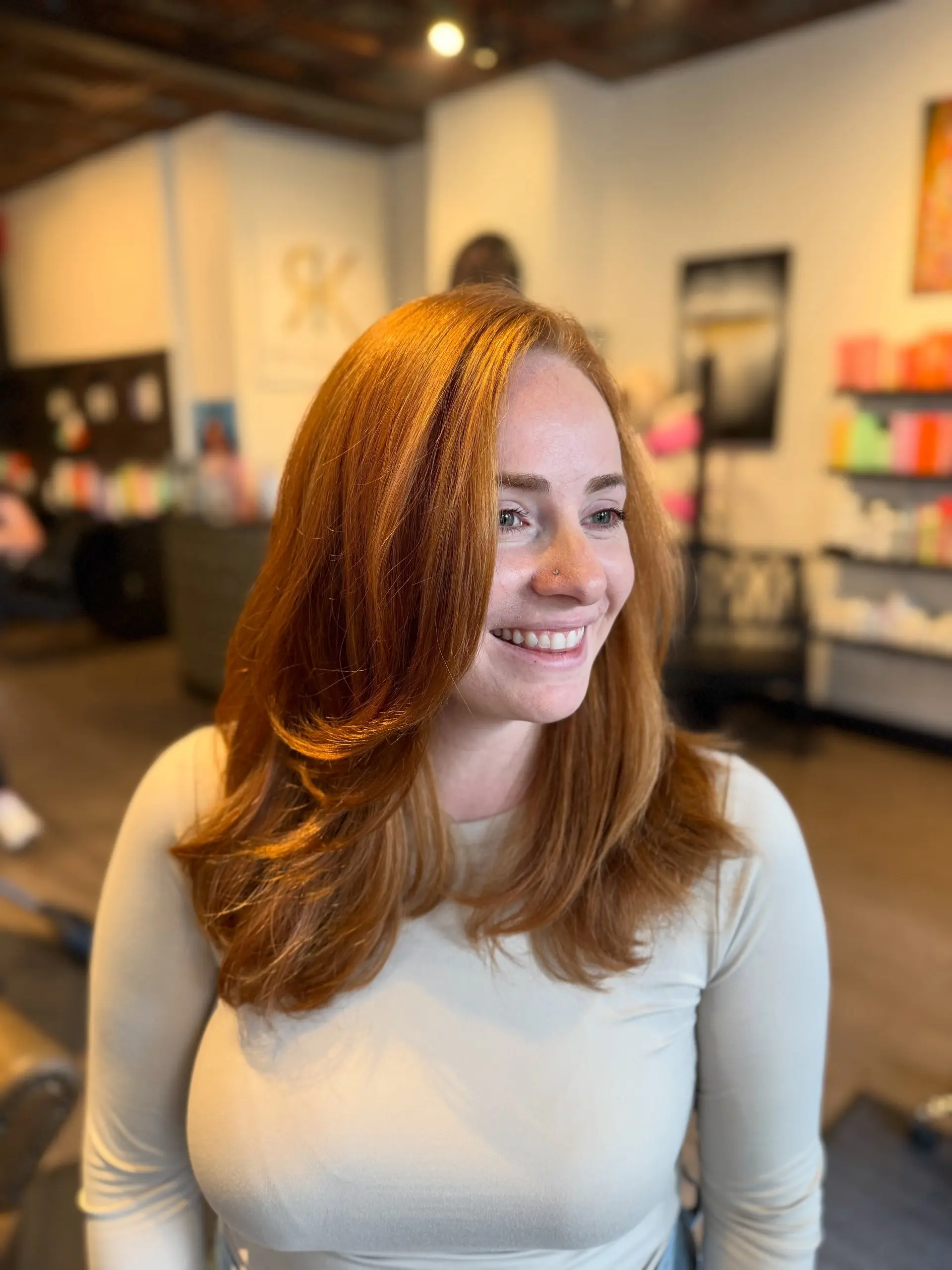 Medium-length bright copper hair cut with soft face-framing layers and styled in a bouncy, voluminous blowout. 1