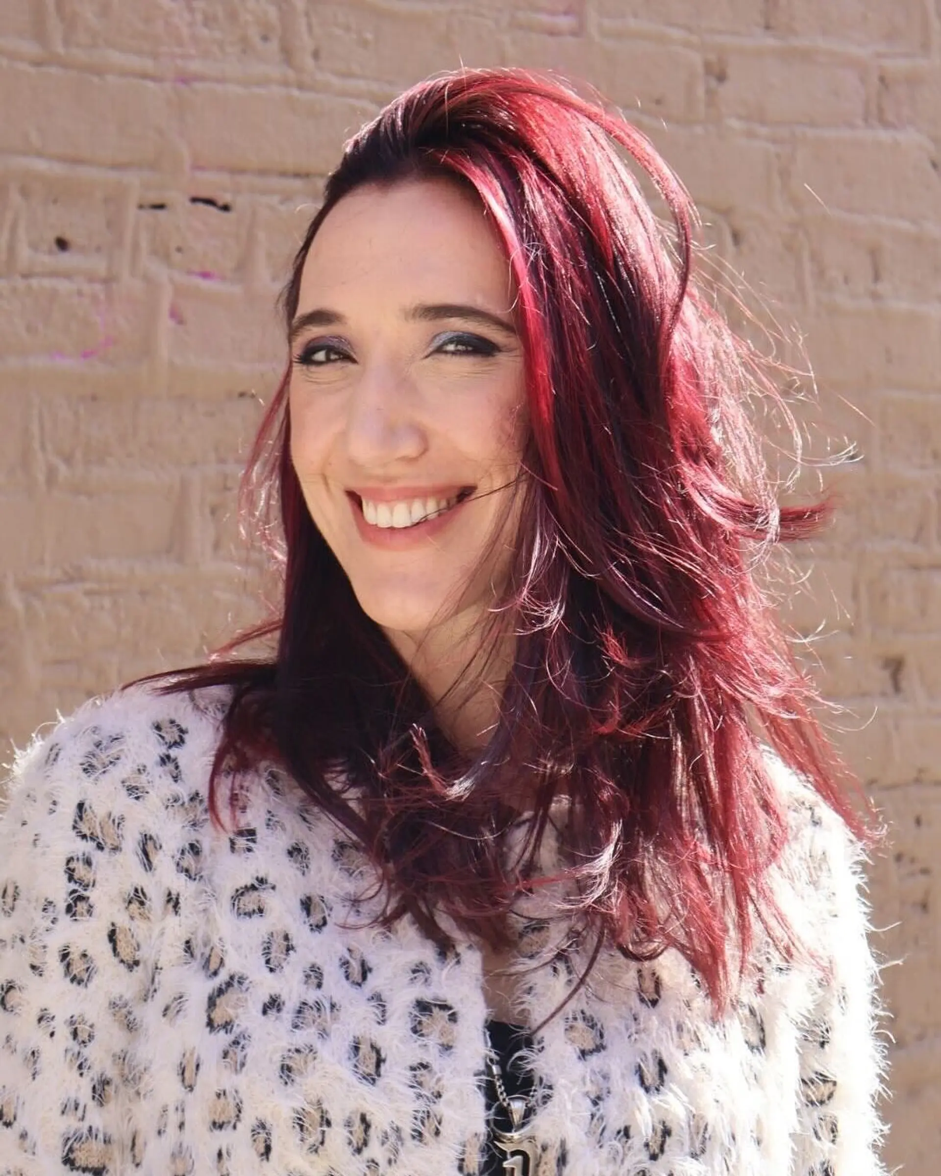 A wavy hairstyle with layered cut and vibrant cherry color. 1