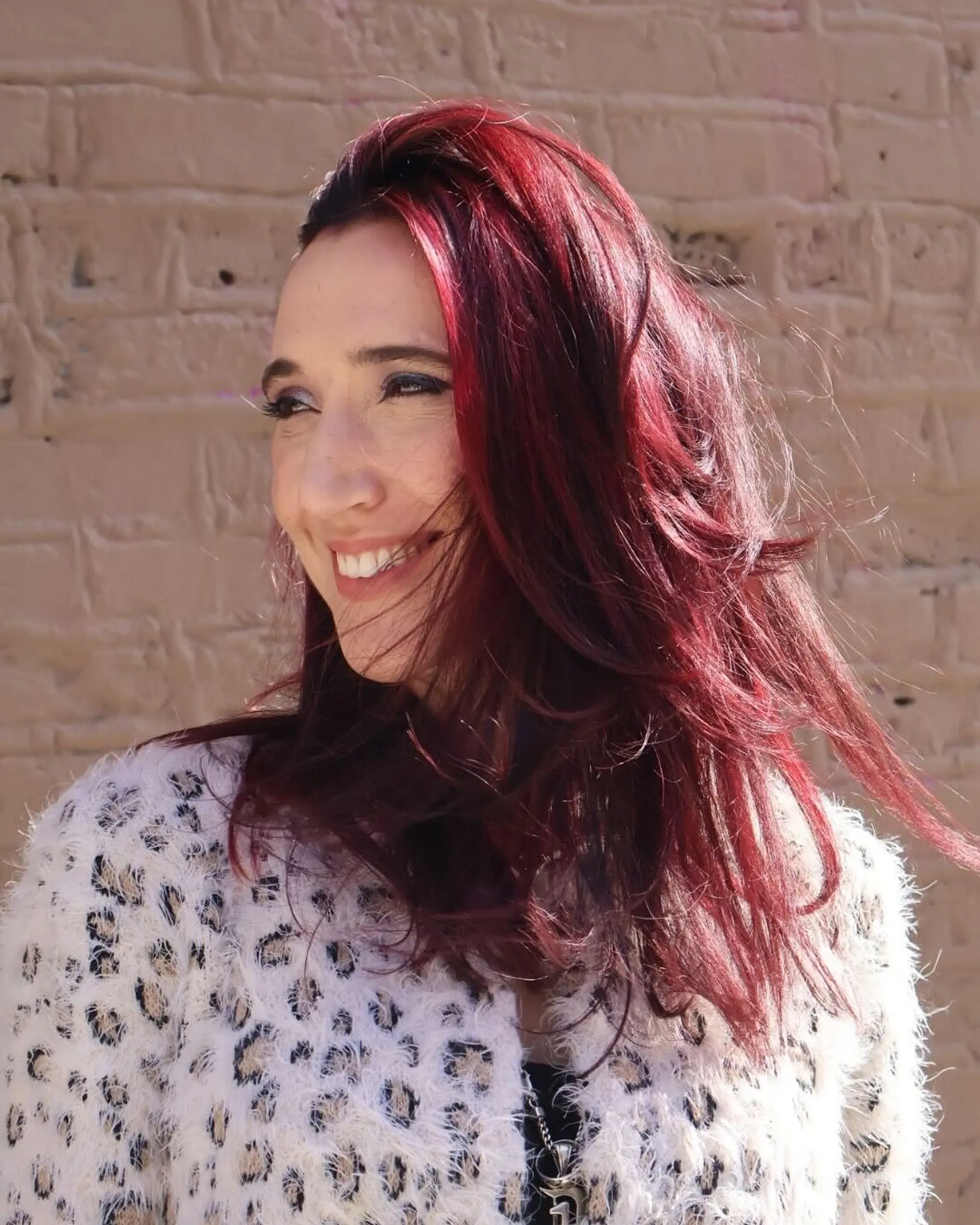 A wavy hairstyle with layered cut and vibrant cherry color. 2