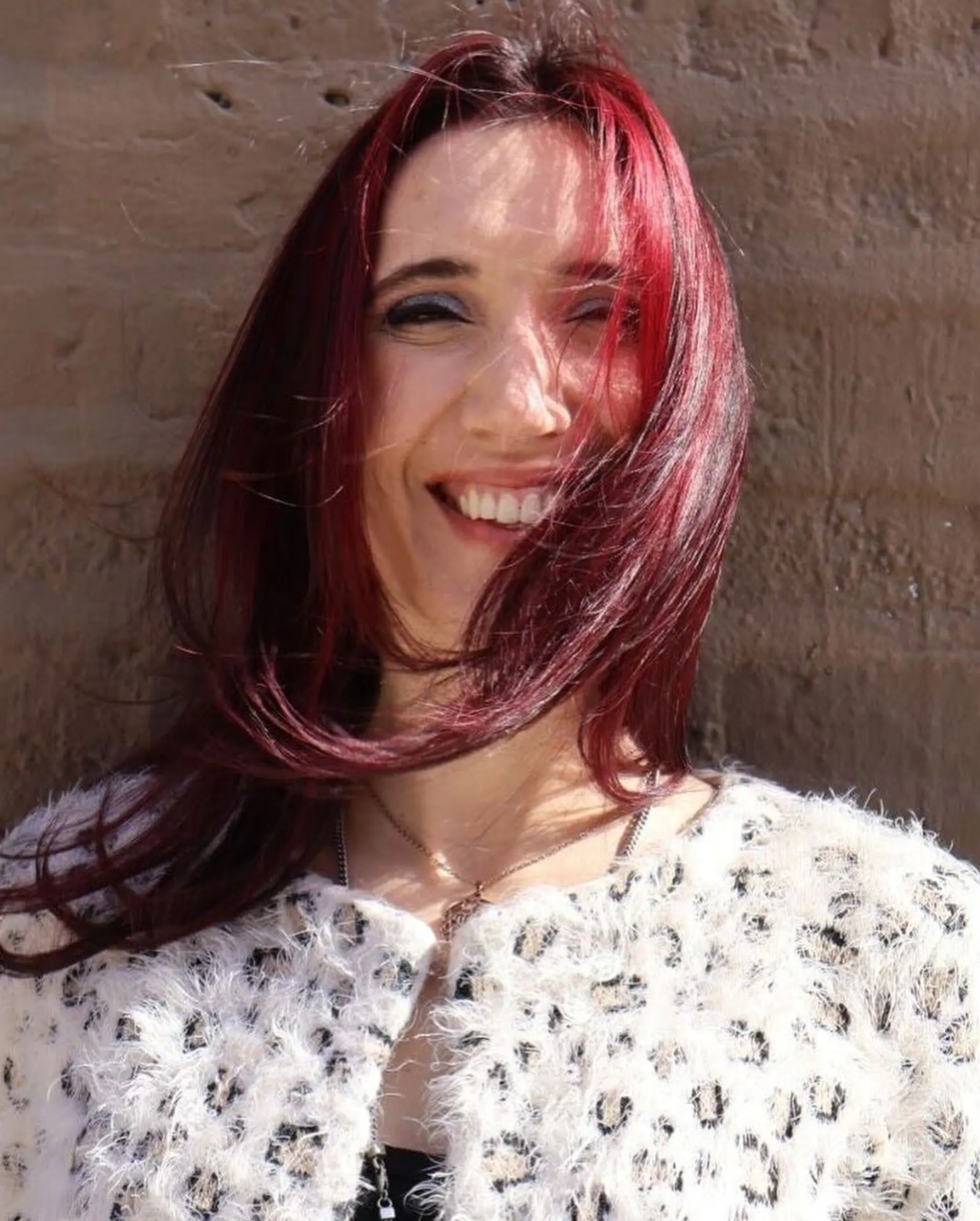 A wavy hairstyle with layered cut and vibrant cherry color. 3