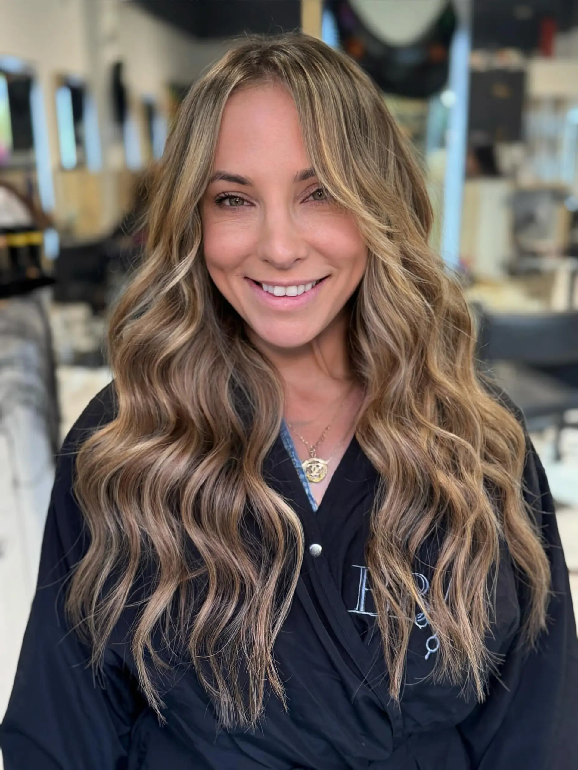 Long layered hair styled with loose beach waves and soft face-framing pieces. 1