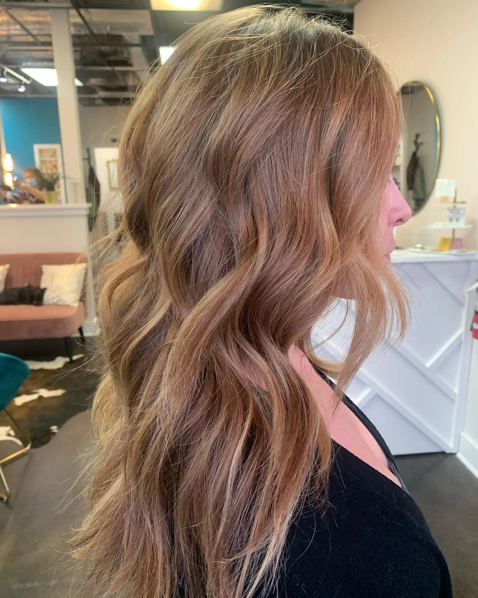 Long hair colored with copper lowlights and golden balayage, styled into soft, flowing beach waves. 1
