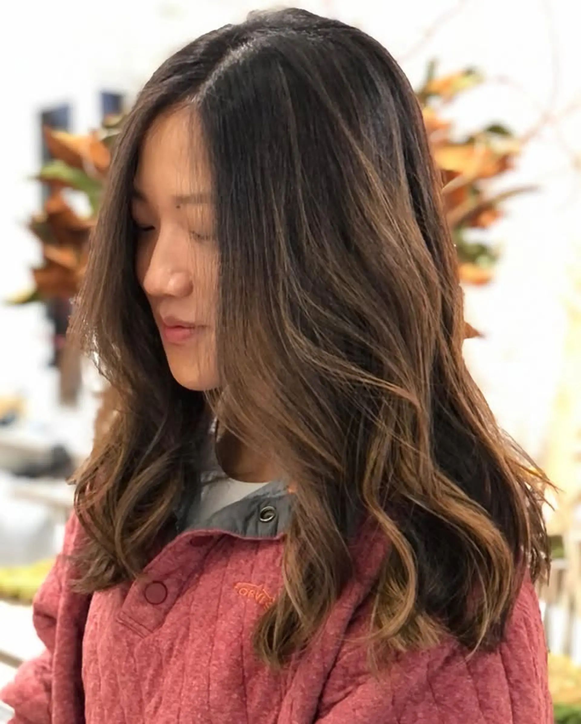 Medium length wavy hair with a bronzed balayage effect. Features subtle layers and soft, flowing waves. 1