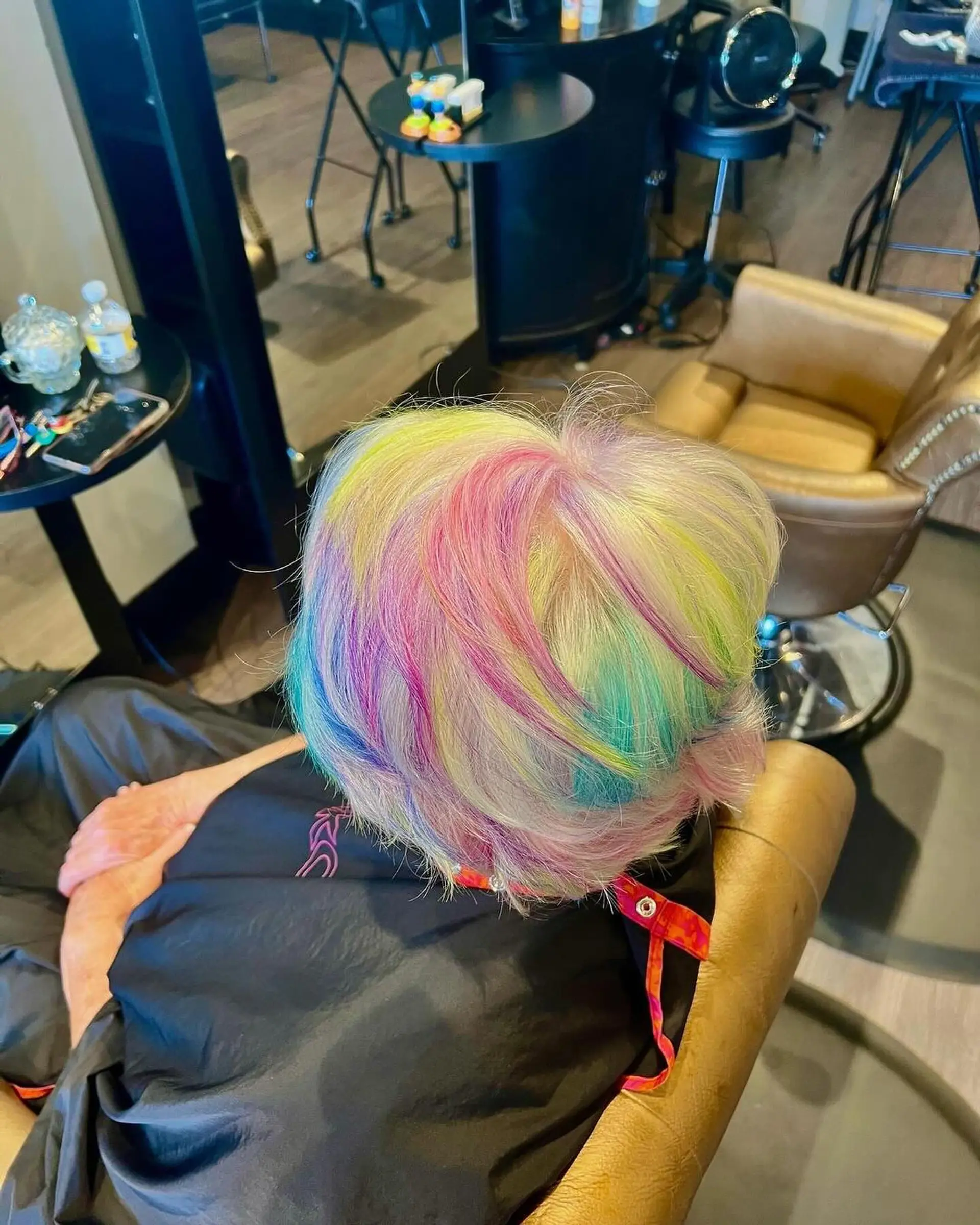 A textured short pixie cut featuring a pale blonde base accented with pastel streaks of pink, yellow, blue, and violet. 1