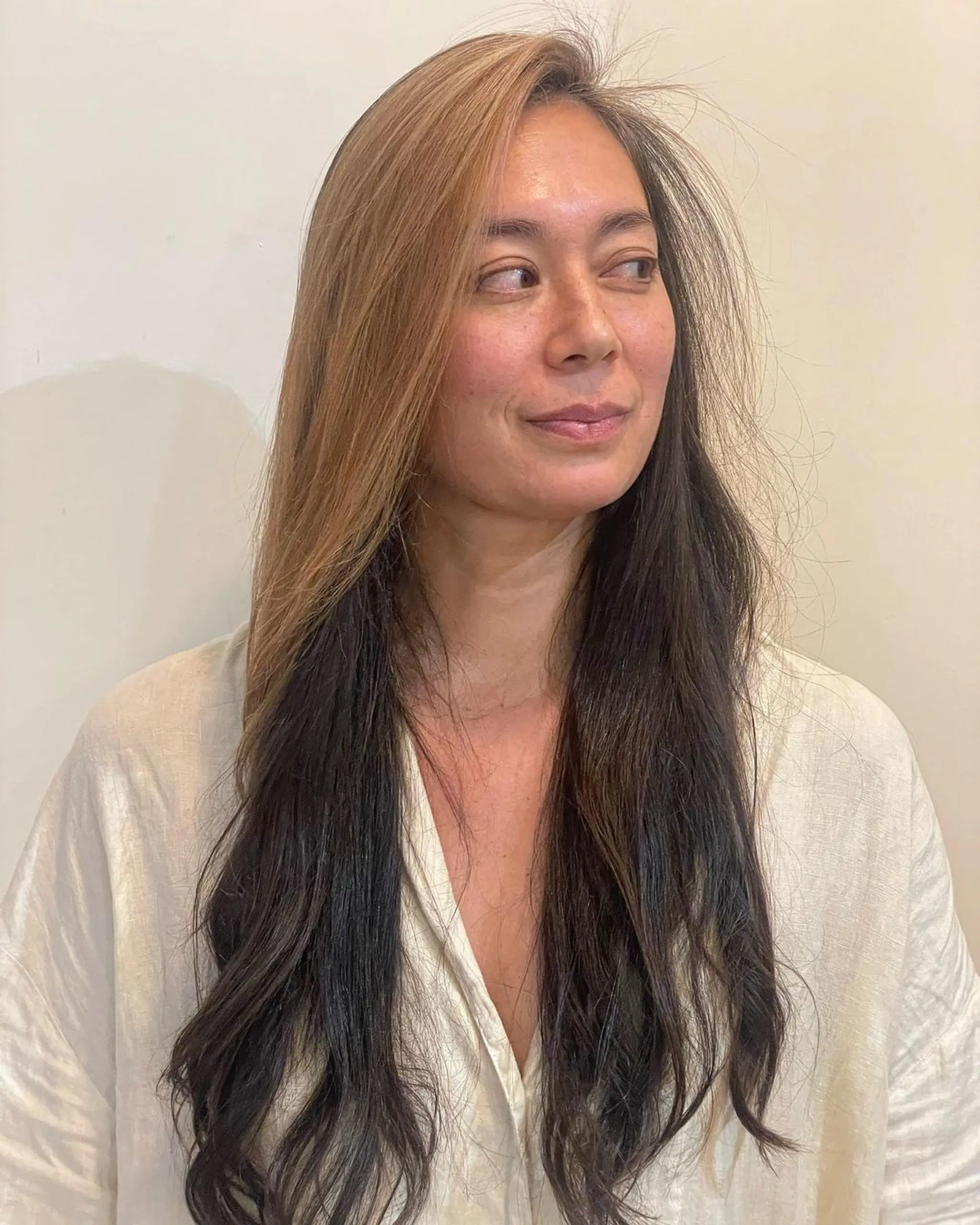 Long, wavy, two-toned hair with dark brown base and blonde highlights. Features a layered, textured style with a soft side part for added elegance.