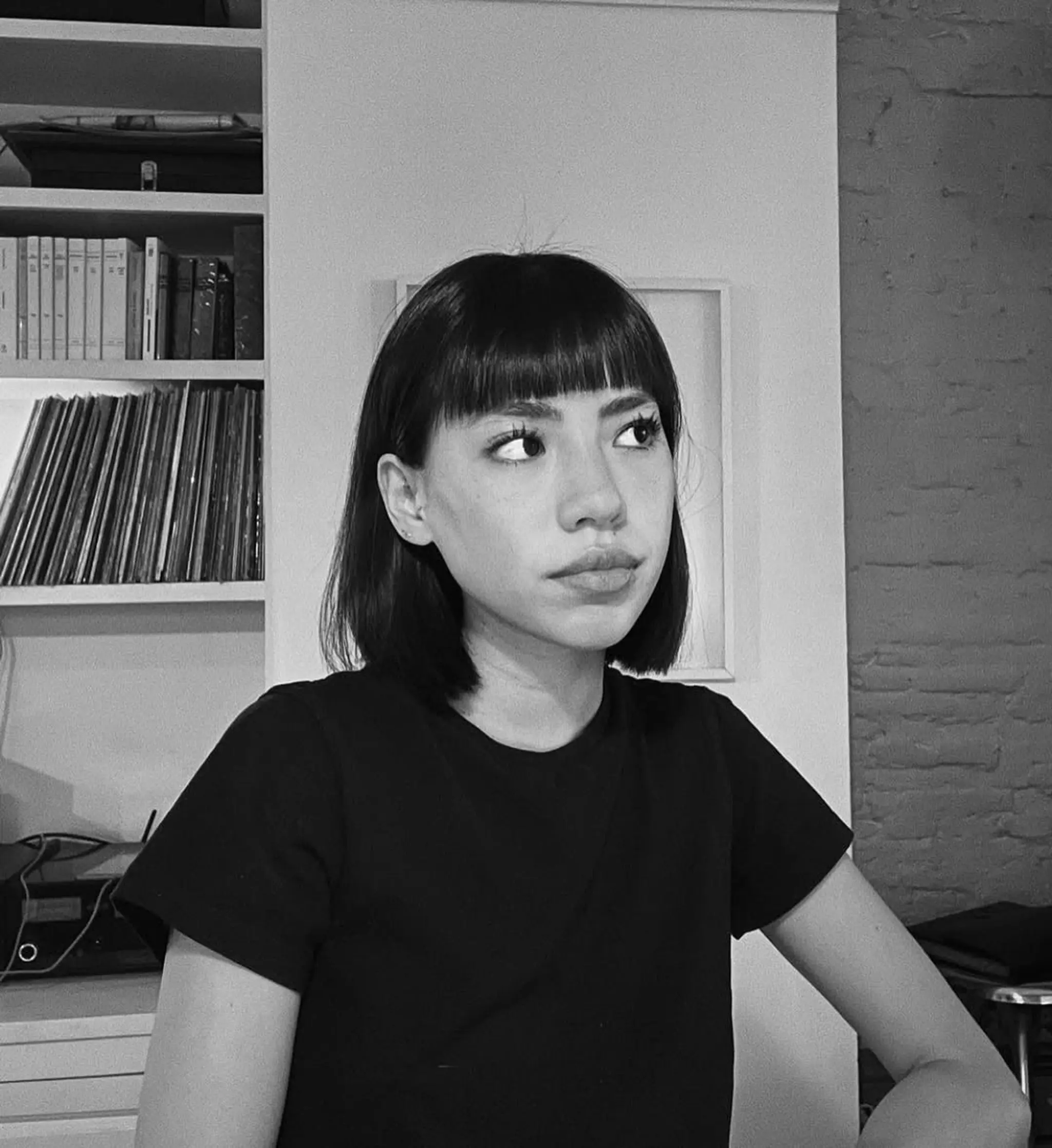 The hairstyle is a sleek and straight short bob with sharp, straight bangs, creating a classic and professional look.