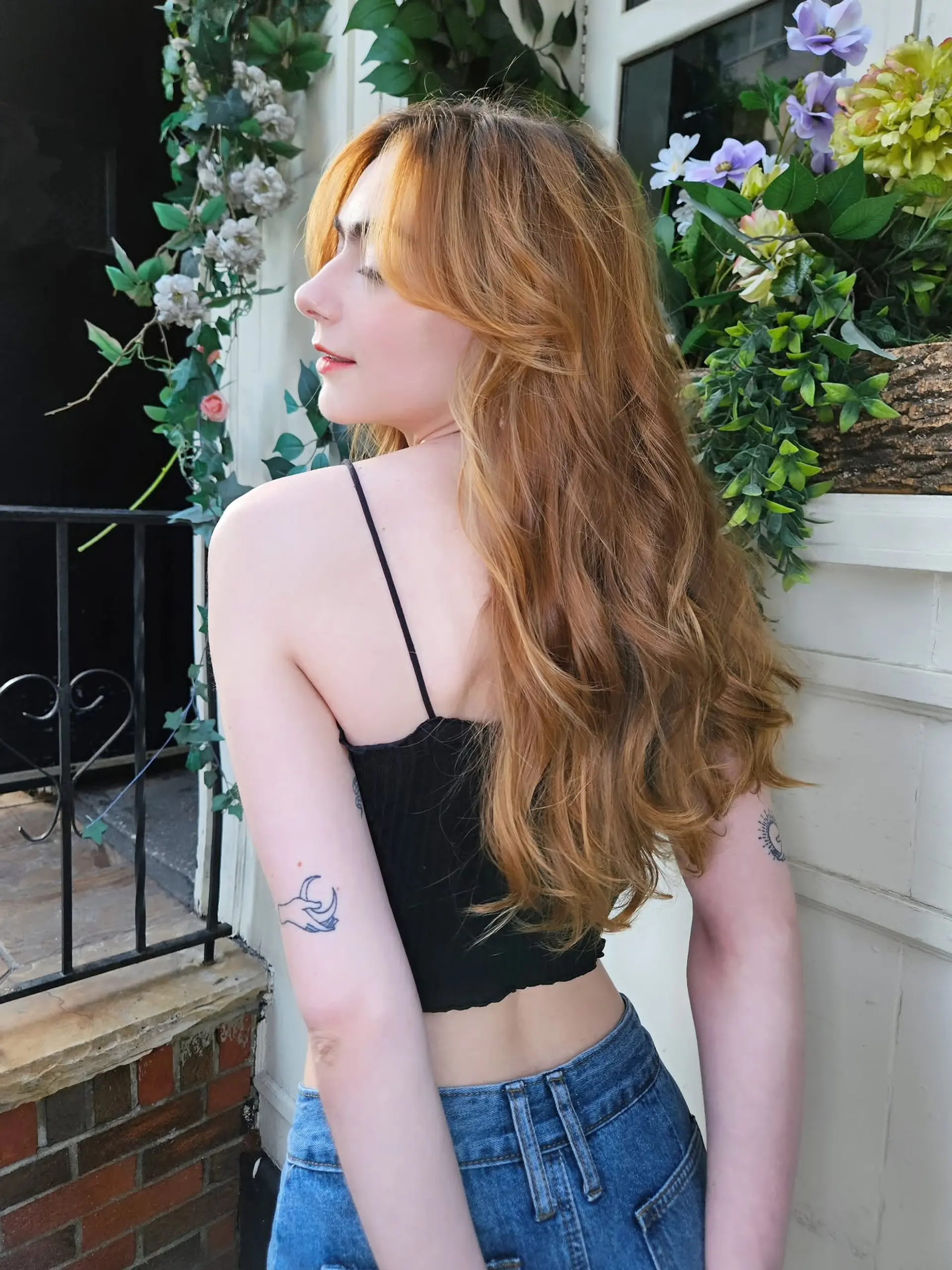 Long warm strawberry blonde hair cut with flowing layers, soft waves, and face-framing curtain bangs. 1