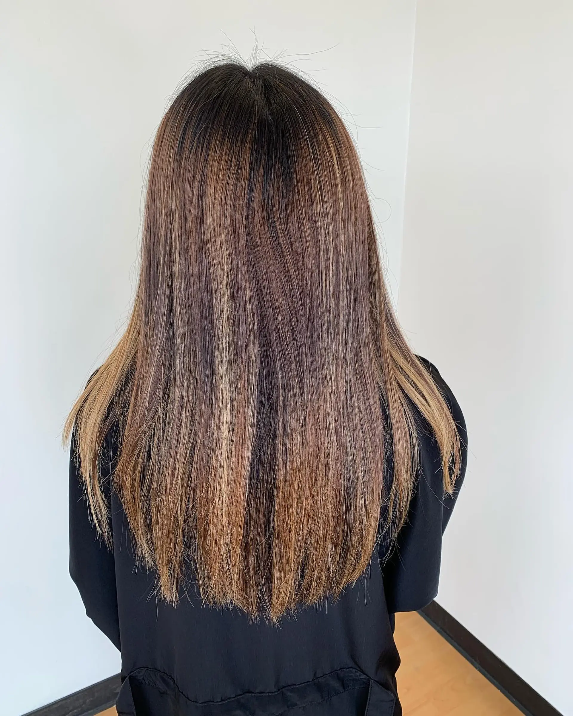 Long, sleek straight hair with multi-tonal warm brown and golden honey highlights blended seamlessly into a dark brown base. 1