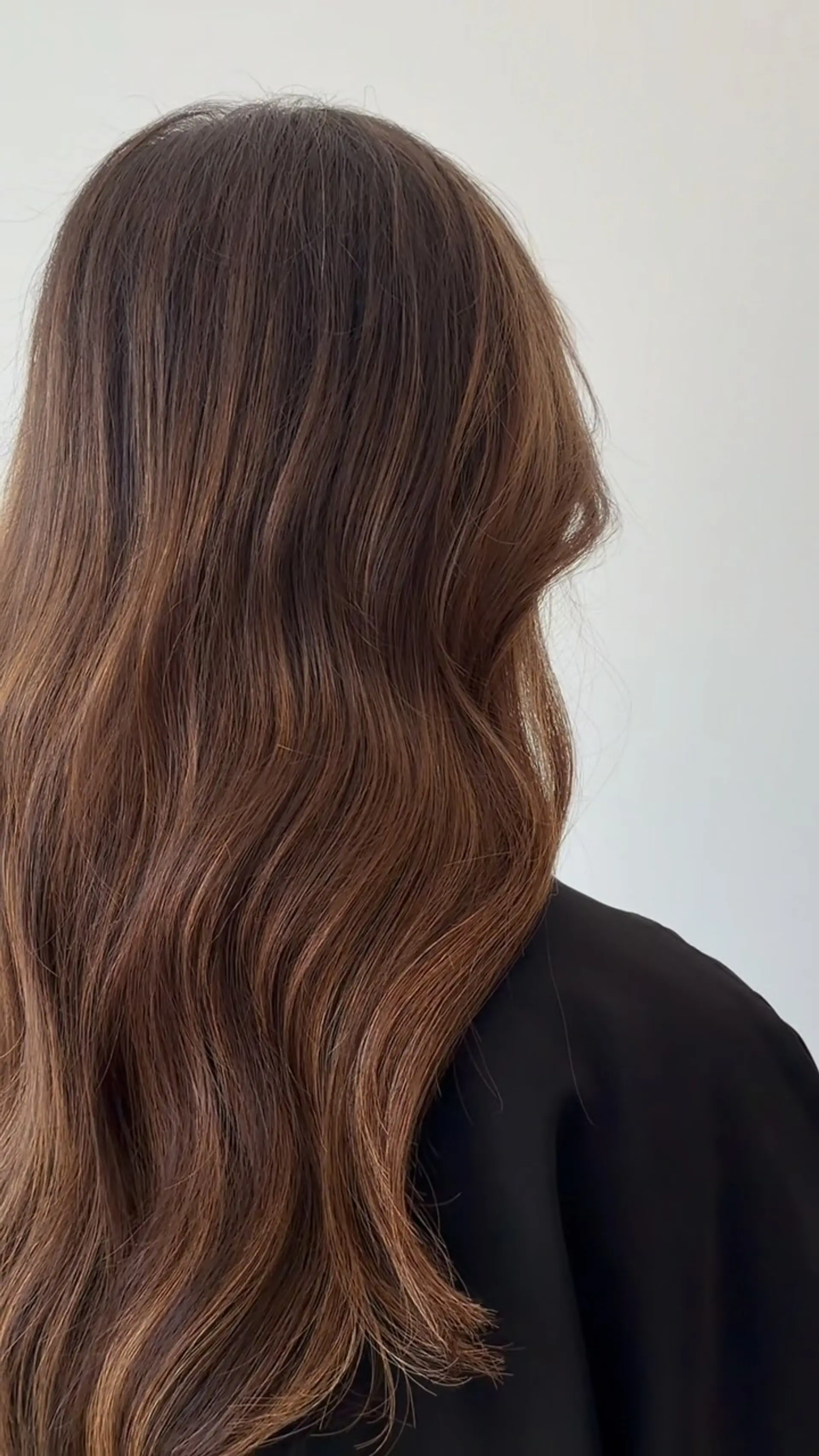 Long, flowing warm brunette hair styled into loose, glossy waves cascading down the back. 1