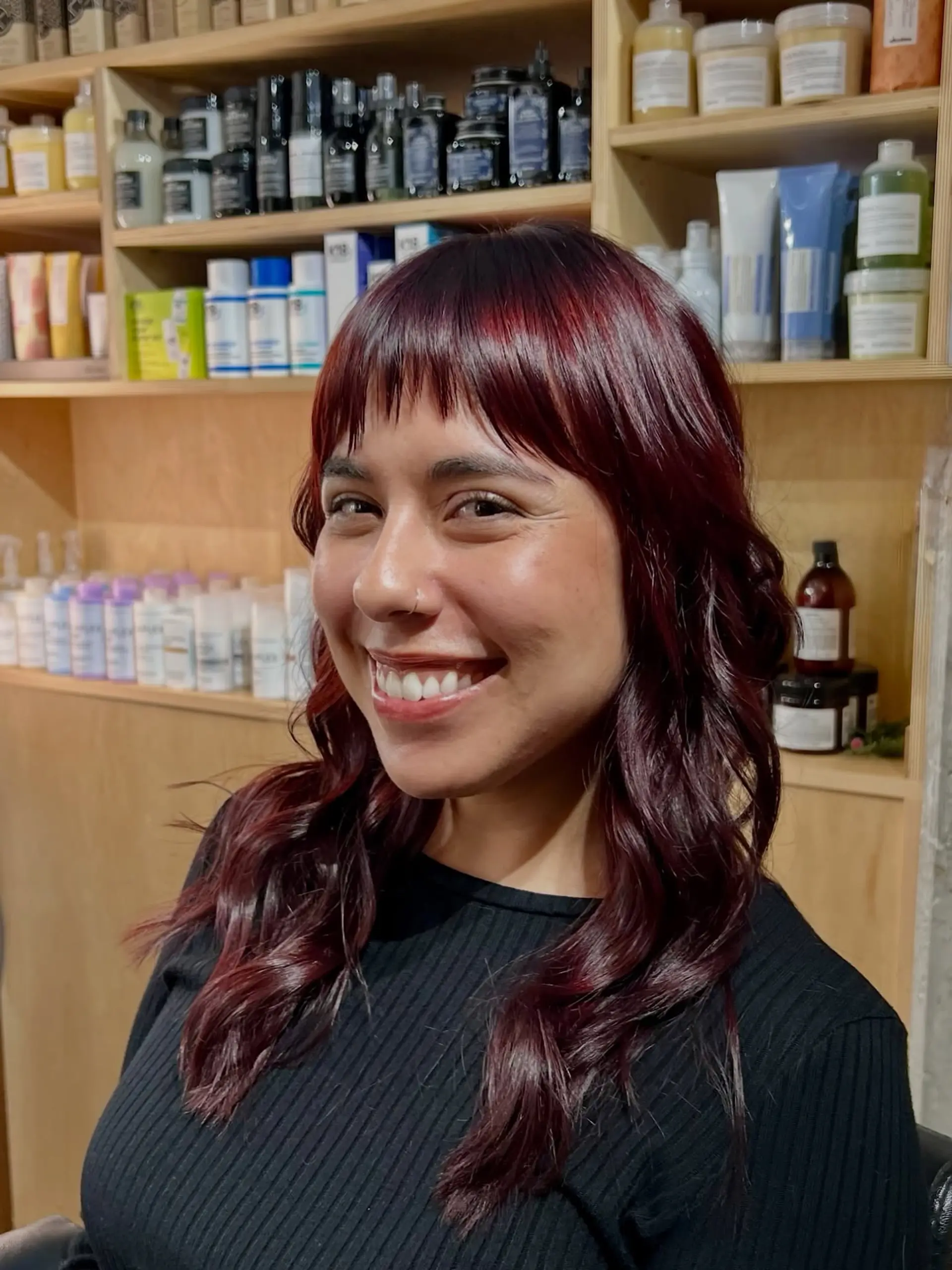Rich cherry cola red hair styled in soft waves with textured fringe bangs. 1