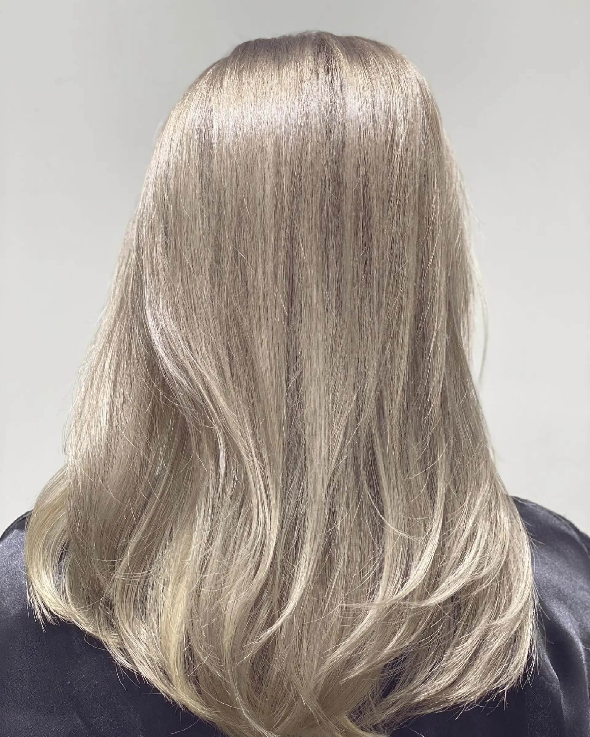 A layered long hairstyle with soft waves, colored in an icy platinum blonde. 1