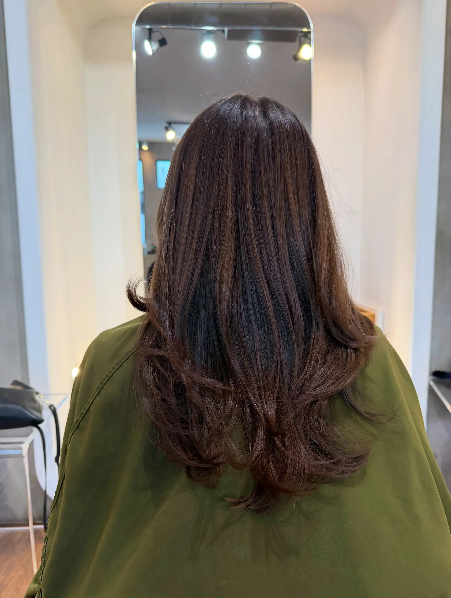 A long, rich chocolate brown haircut styled with flowing soft layers and gentle flips at the ends for natural movement. 1