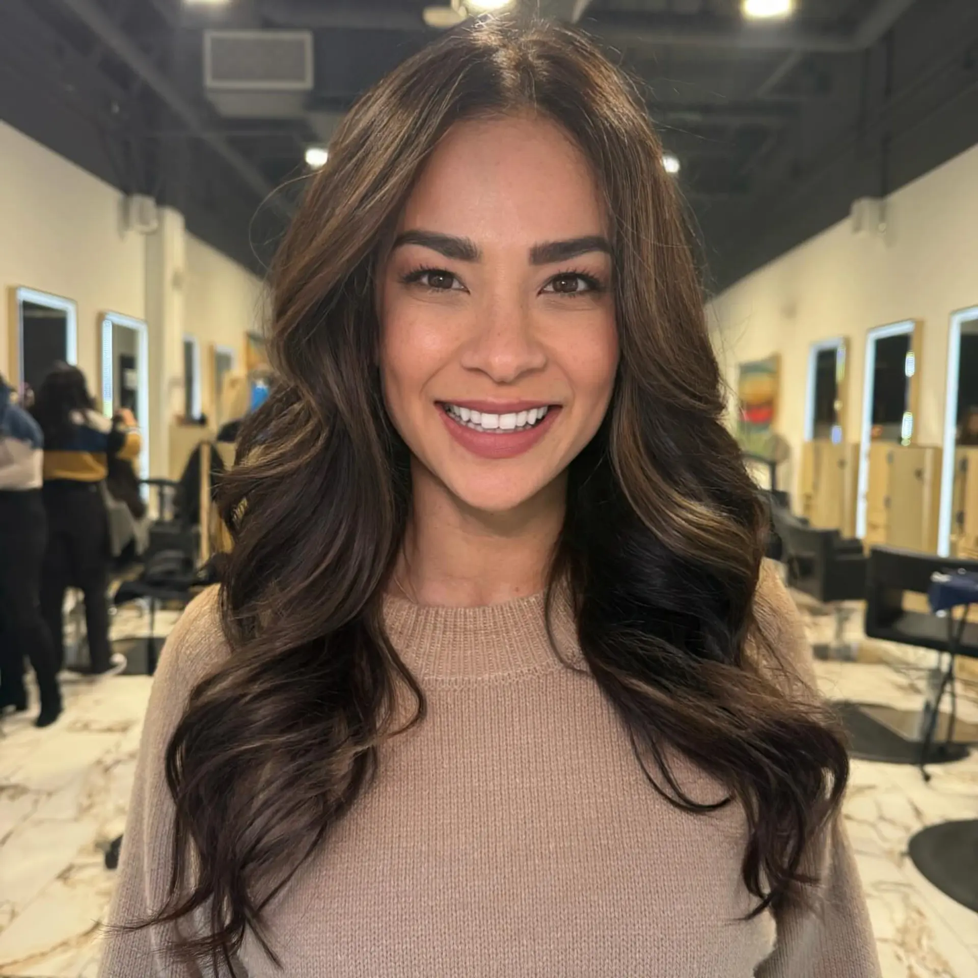 Long dimensional brunette hair cut and styled into soft, voluminous waves. 1