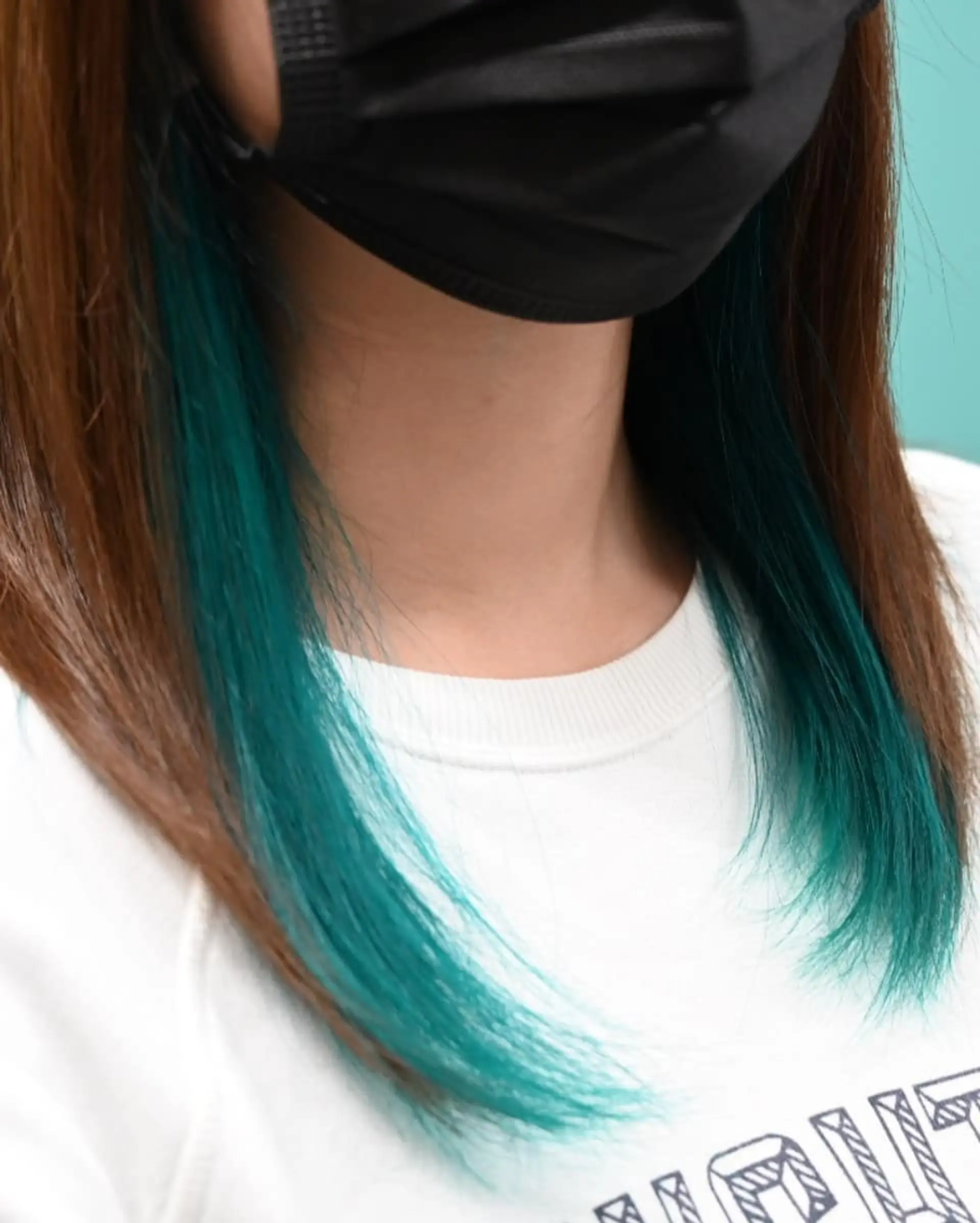 Medium-length straight brown hair showcasing vibrant teal peekaboo highlights beneath the top layer. 1