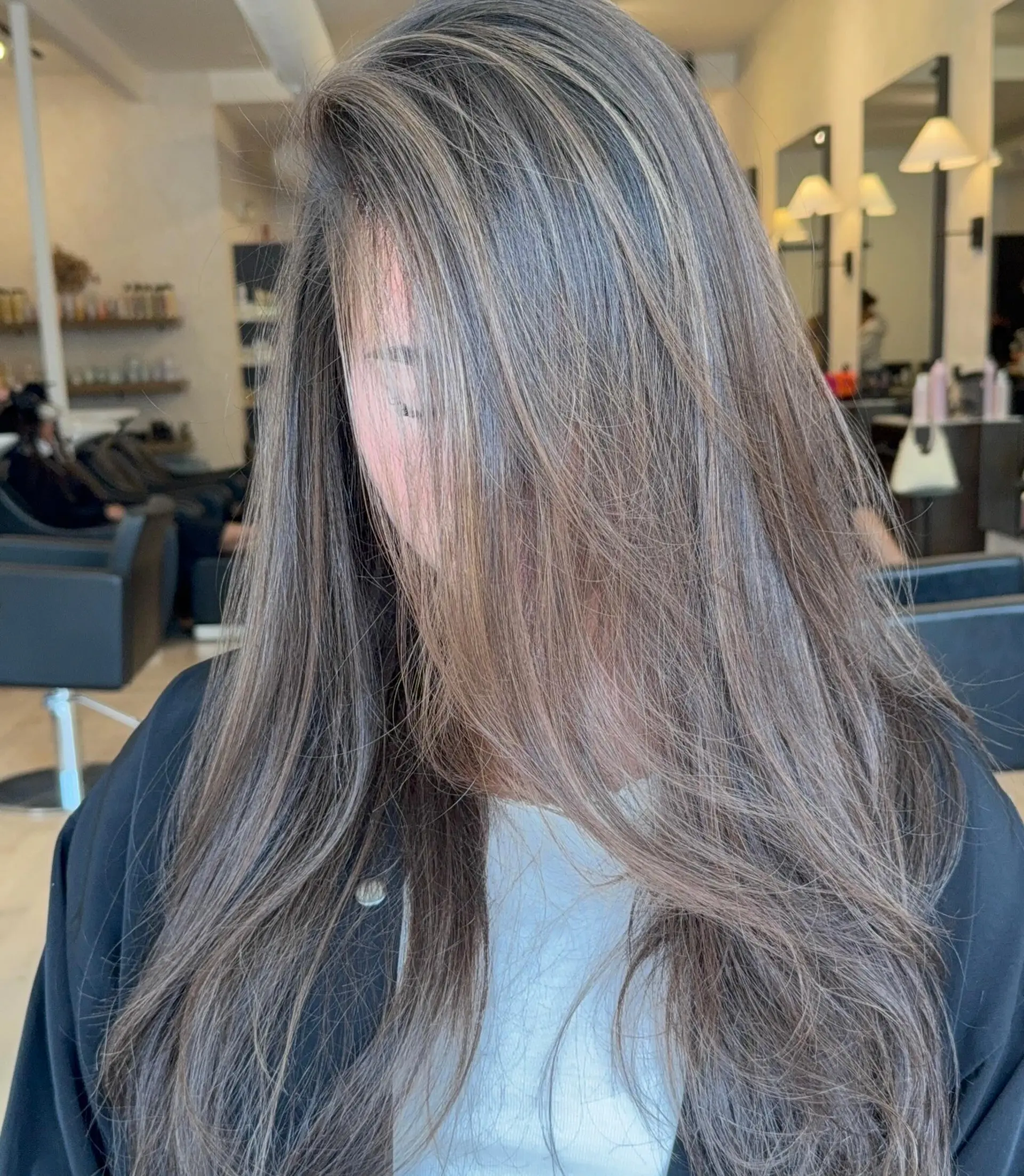 Long, cool-toned brunette hair styled with a smooth blowout and dimensional, finely woven ash highlights. 1