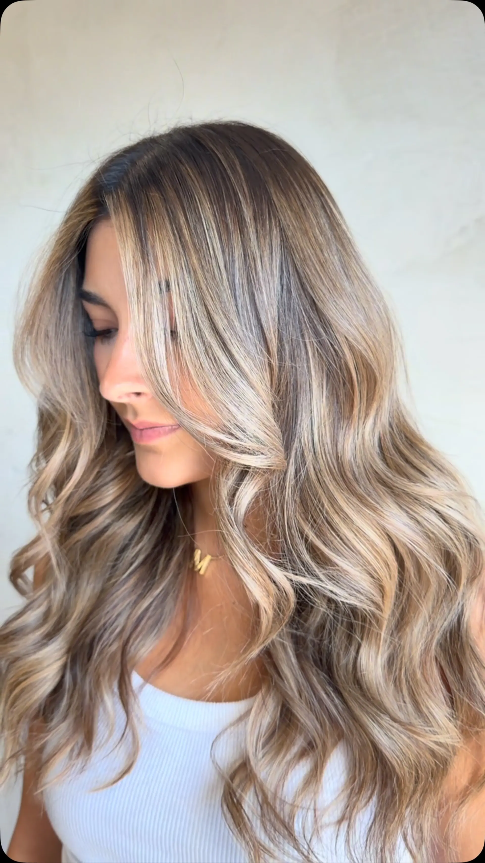 Long, flowing waves styled with seamless cool and beige blonde highlights blended into a soft root shadow. 1