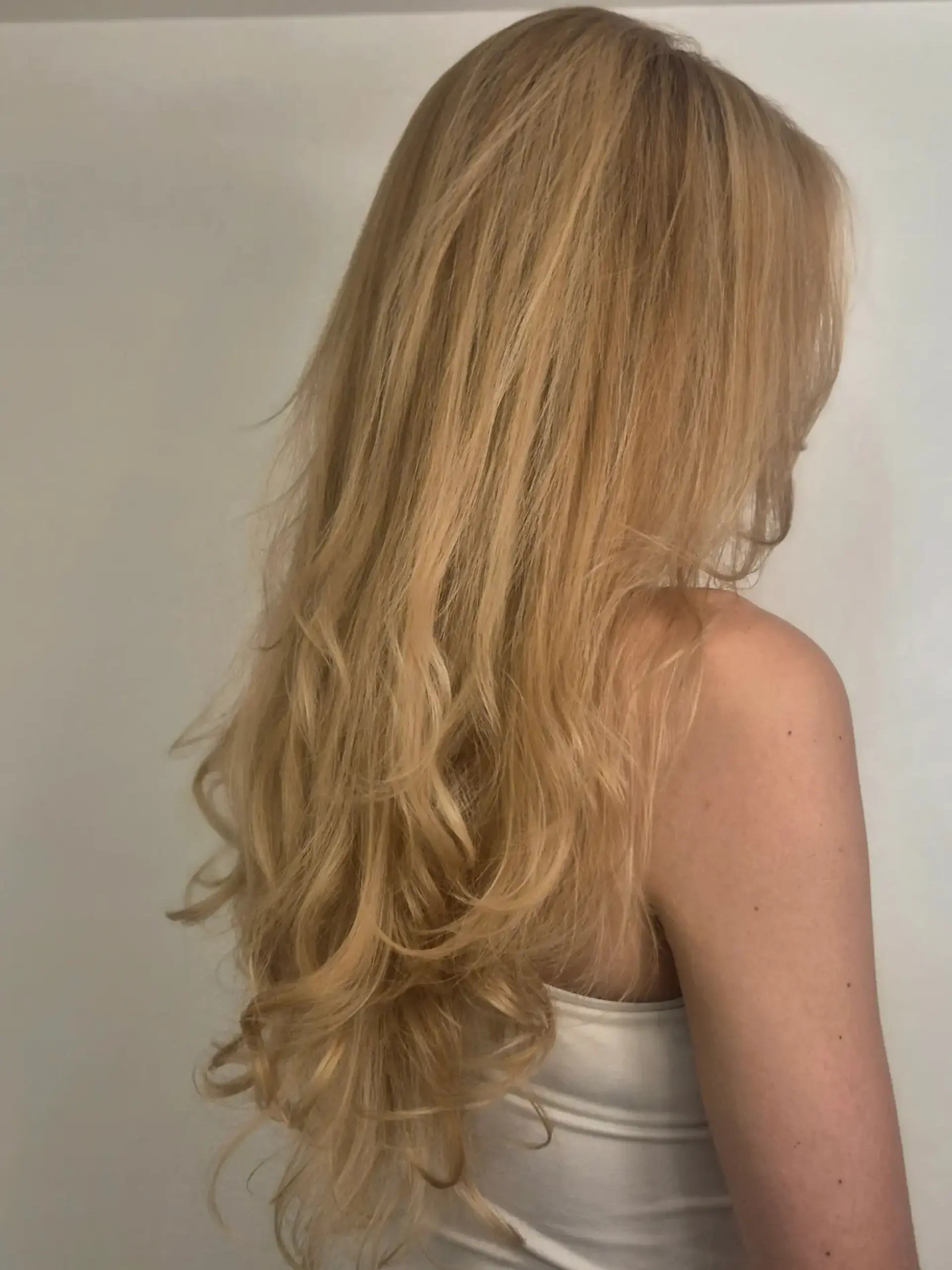 Long warm golden blonde hair cut with flowing layers and finished with soft, bouncy curls at the ends. 1