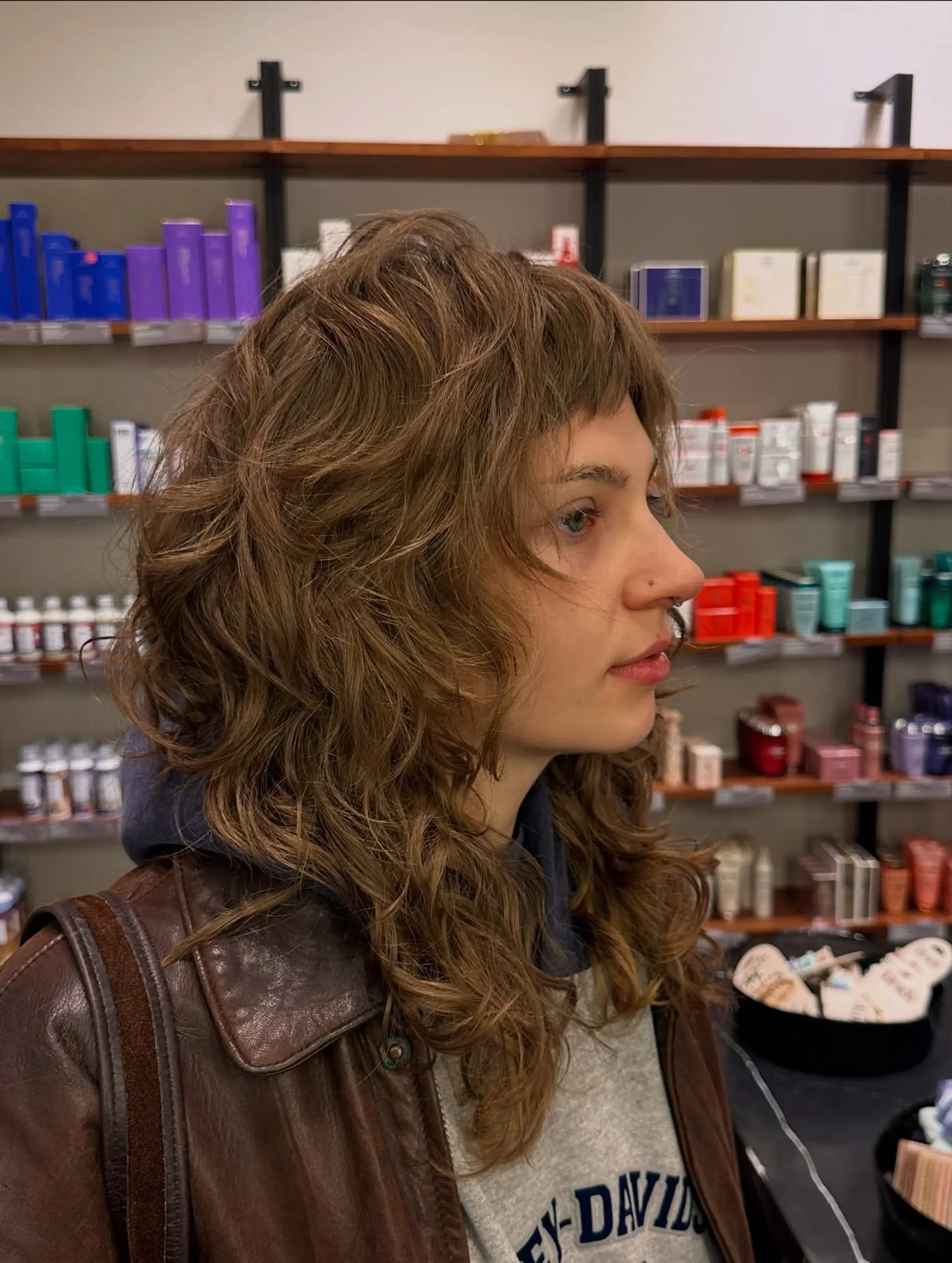 A textured modern shag featuring heavily cut disconnected layers, voluminous crown shape, loose natural waves, and short choppy baby bangs. 1