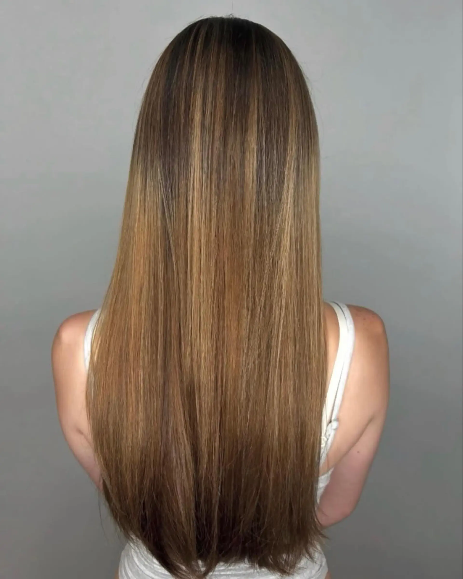Long, sleek straight hair with finely blended caramel and golden blonde partial highlights over a natural brown base. 1