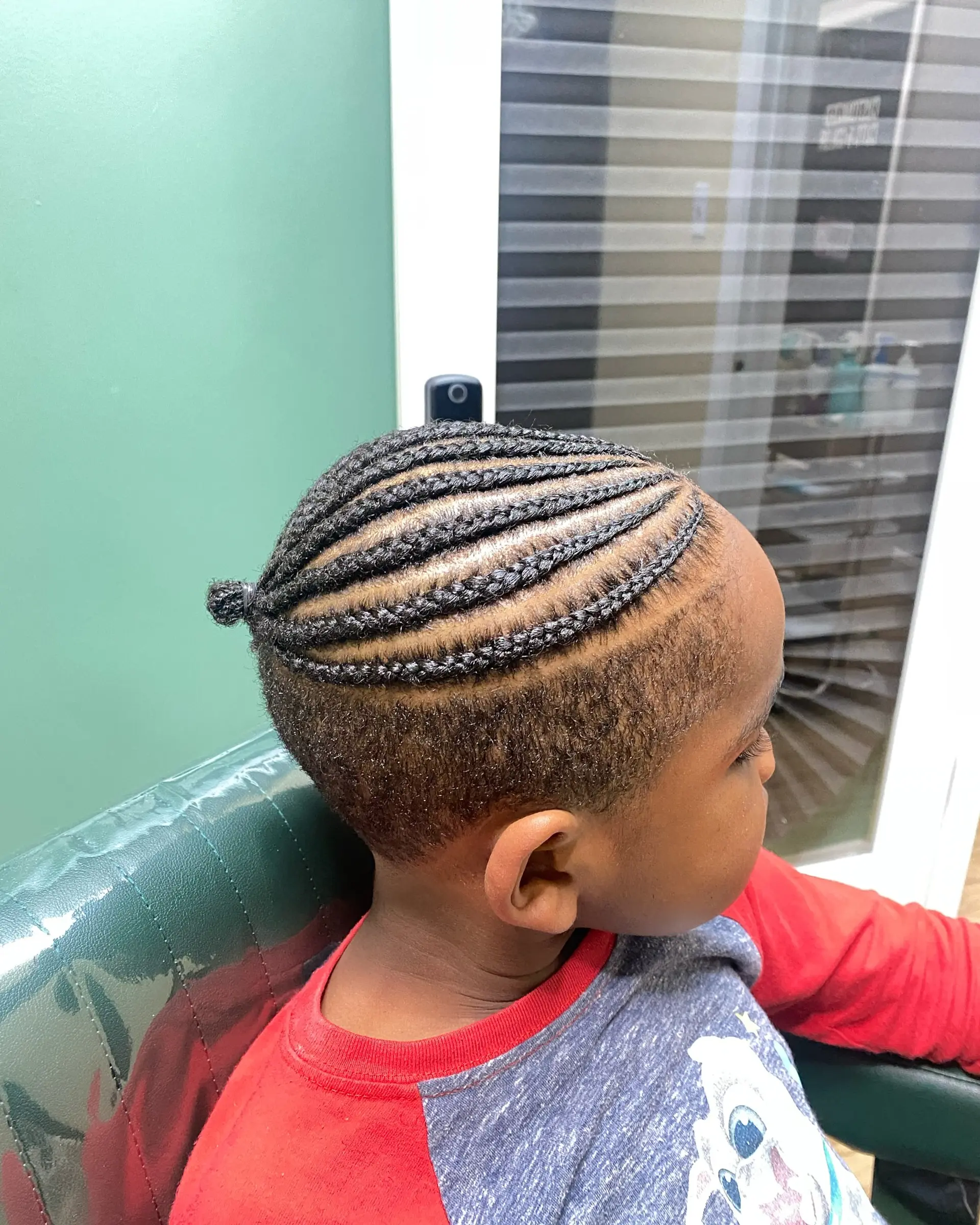 Sleek, curved cornrows styled across the top into a small bun, paired with a short taper fade on the sides. 1