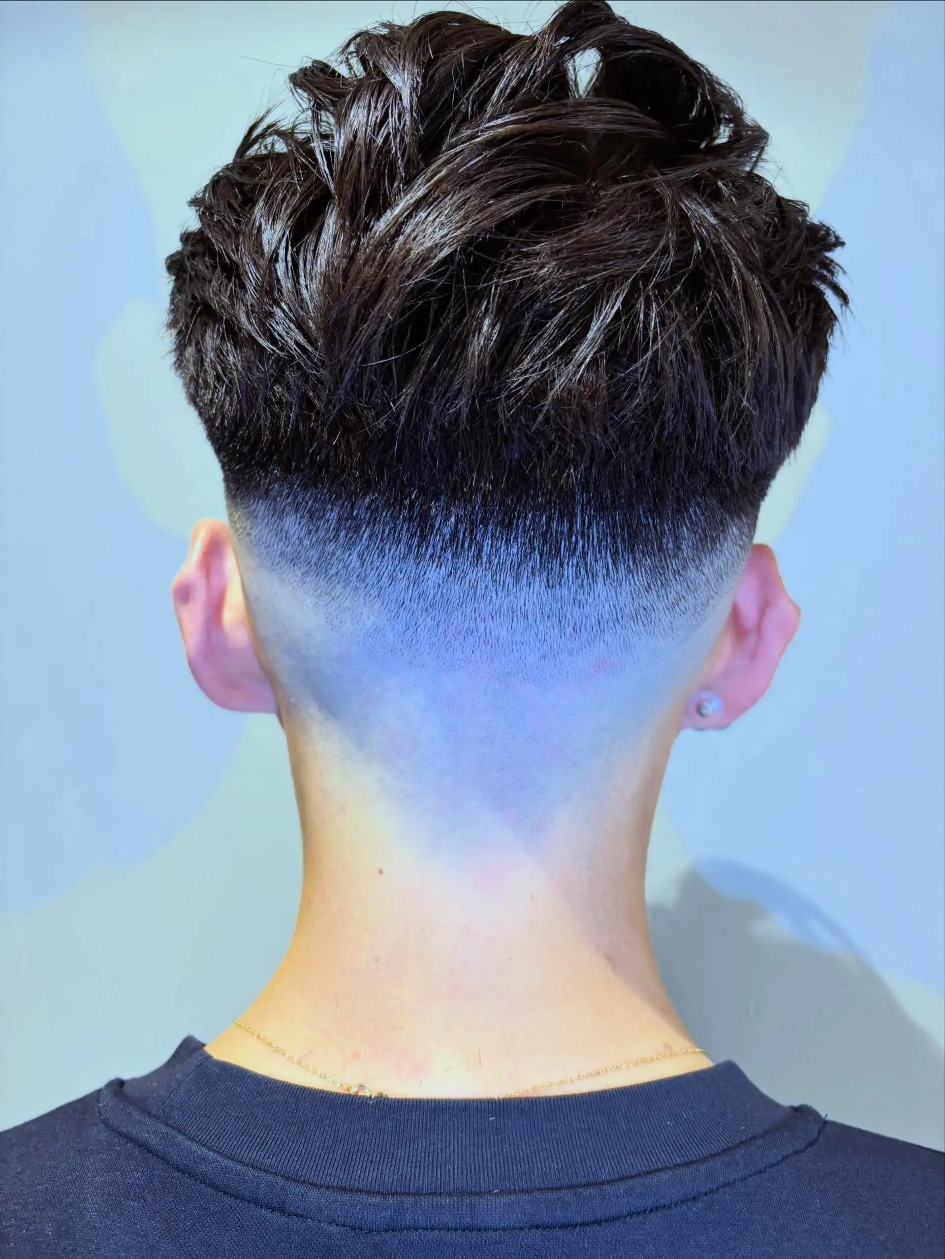 A clean low skin taper fade at the nape paired with a textured, voluminous top styled with defined separation. 1
