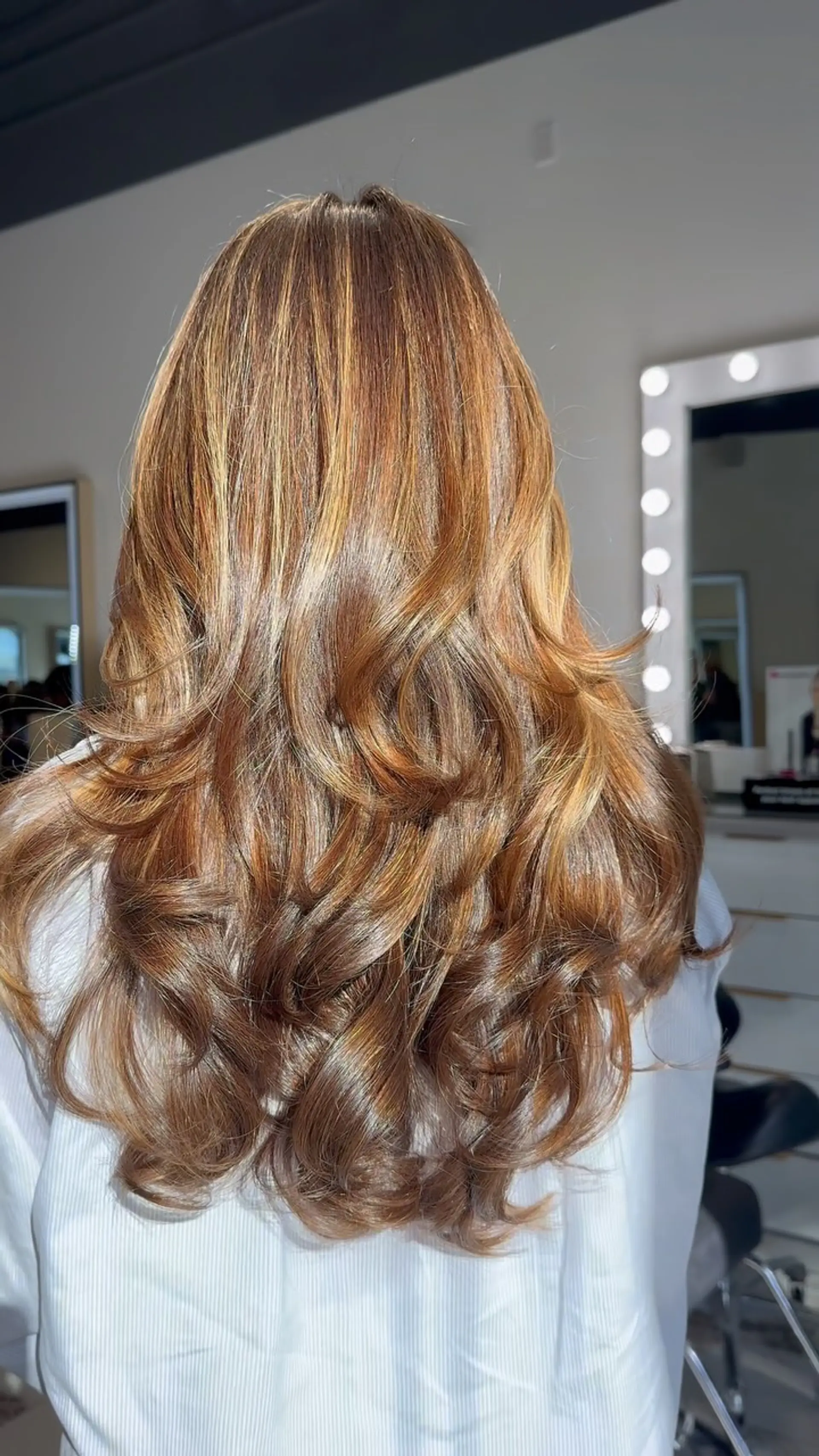 Long cascading layers in a warm brown base highlighted with golden caramel tones, styled into bouncy curled ends. 1