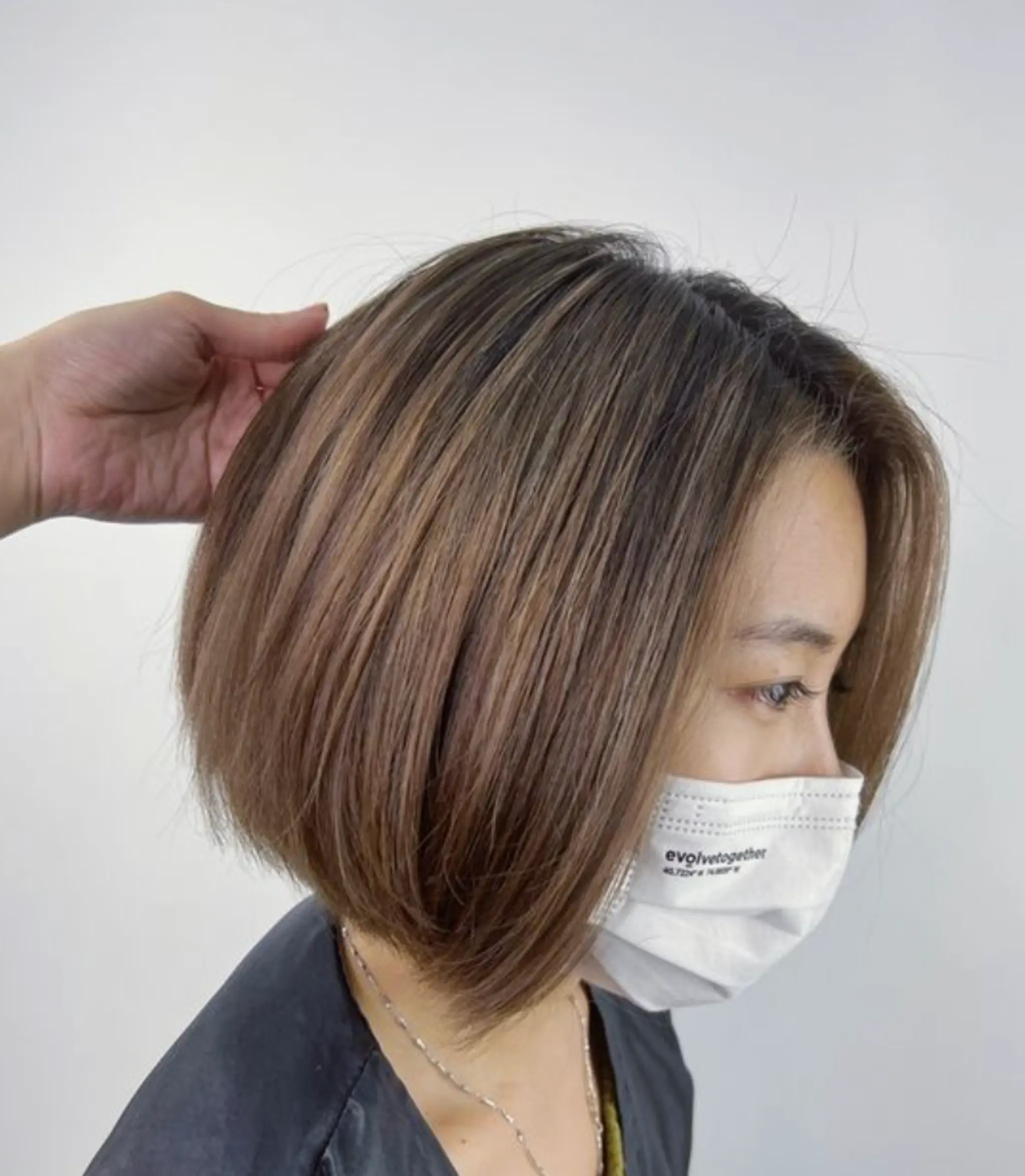 A smooth, straight bob with graduated layers, ending just above the shoulders creating a soft, voluminous look with a subtle side part.