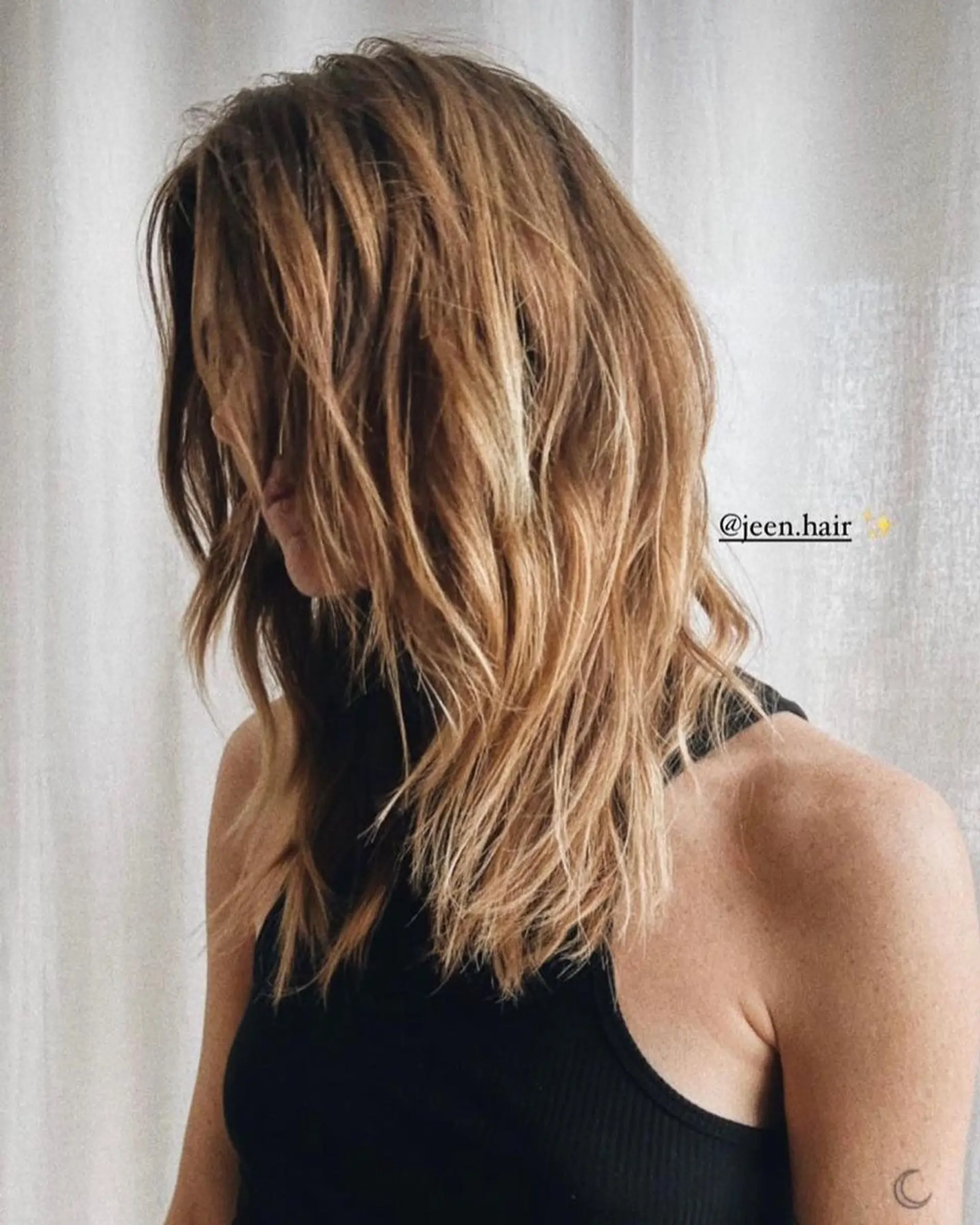 Long, wavy hair with layered cuts and sun-kissed honey blonde highlights, creating natural movement and dimension. 1