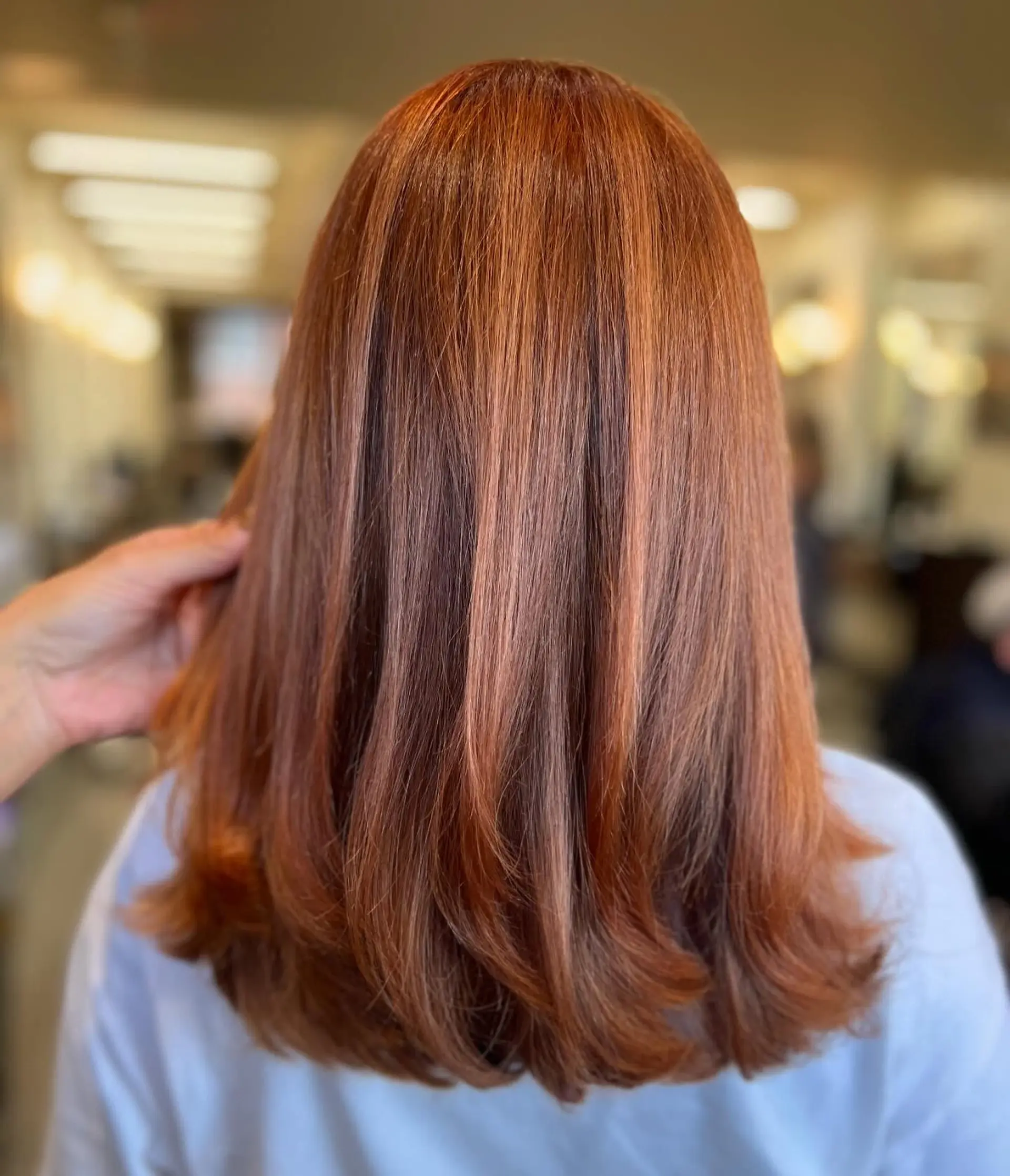 A rich, dimensional copper-red color styled into a sleek blowout with soft, turned-under layered ends. 1