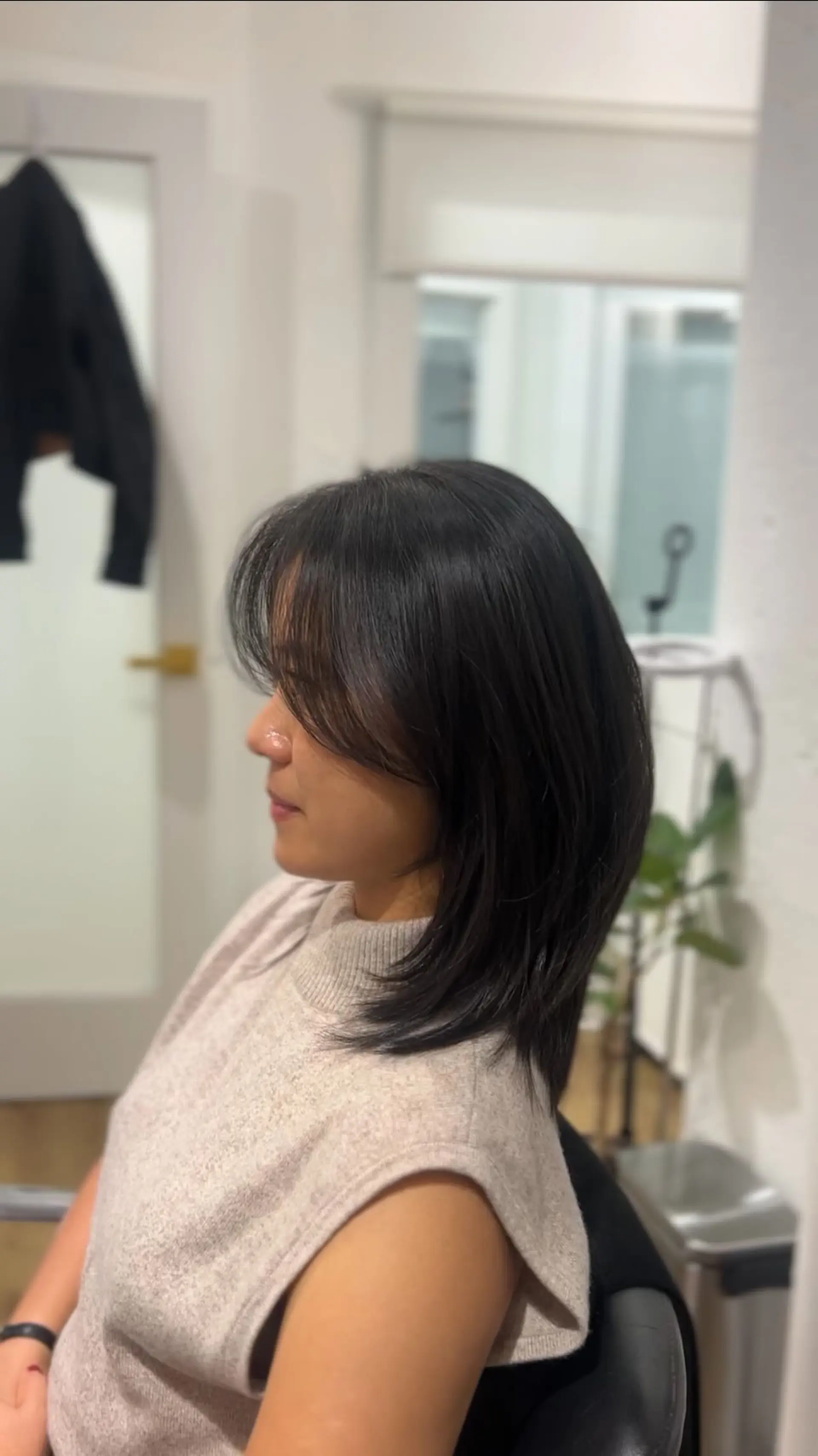 A medium-length straight dark haircut featuring textured layers and soft, face-framing wispy bangs. 1