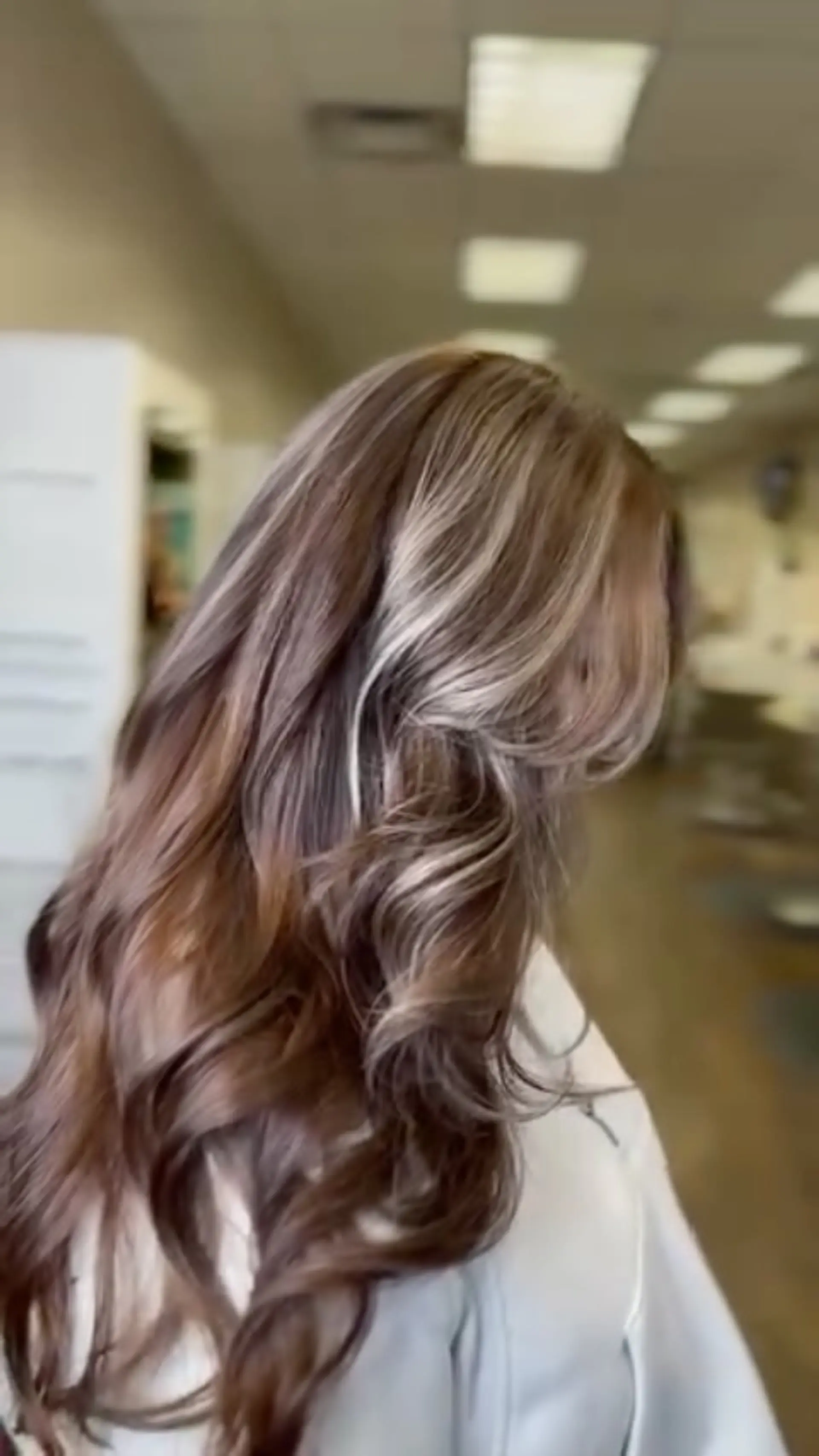 Long wavy dimensional brunette hair styled with contrasting blonde balayage and bright face-framing highlights. 1