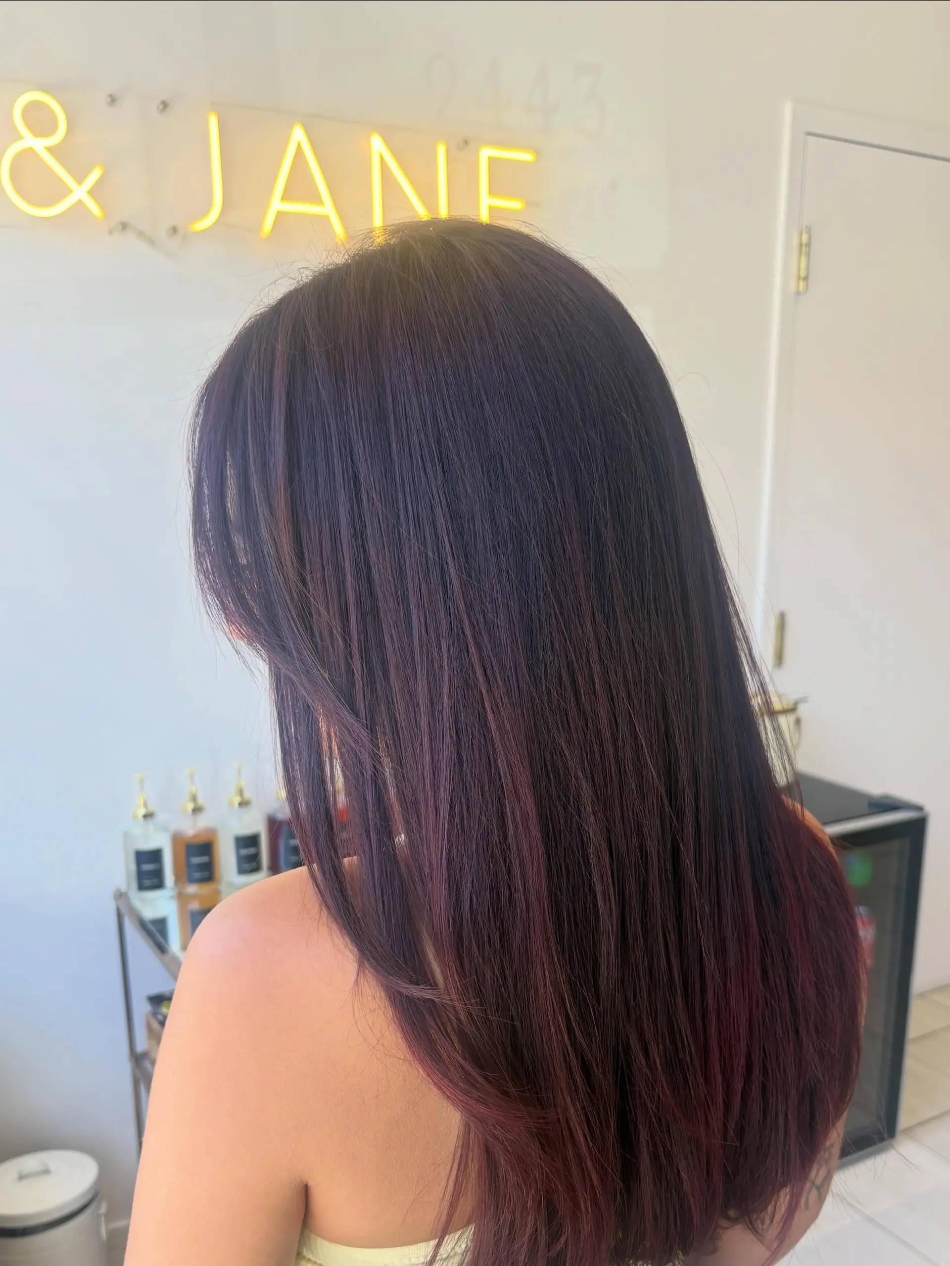 Long, sleek straight hair finished in a rich, glossy cherry cola and burgundy tone. 1