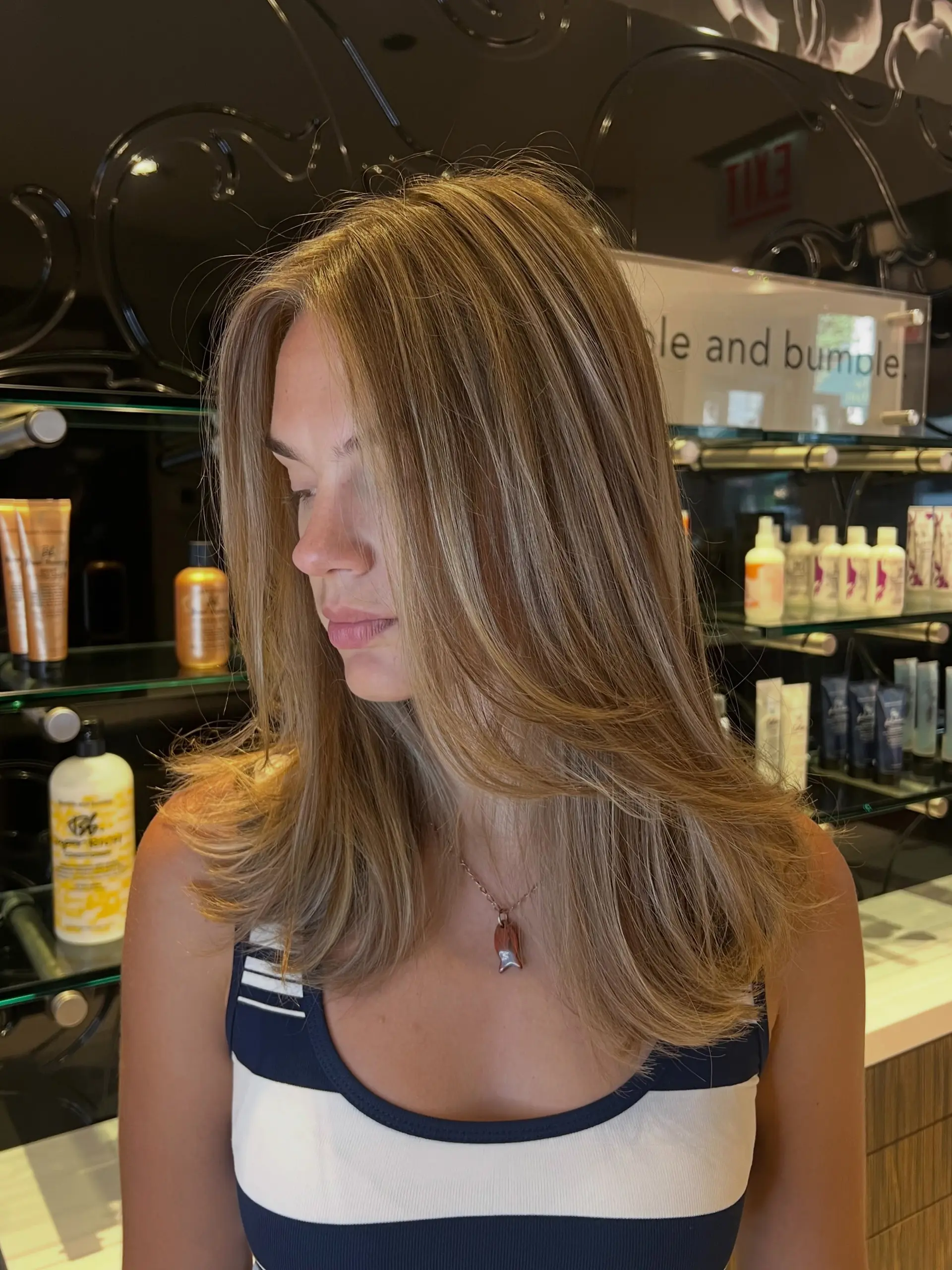 Medium to long layered hair featuring a warm lived-in blonde balayage styled with a smooth, voluminous blowout. 1