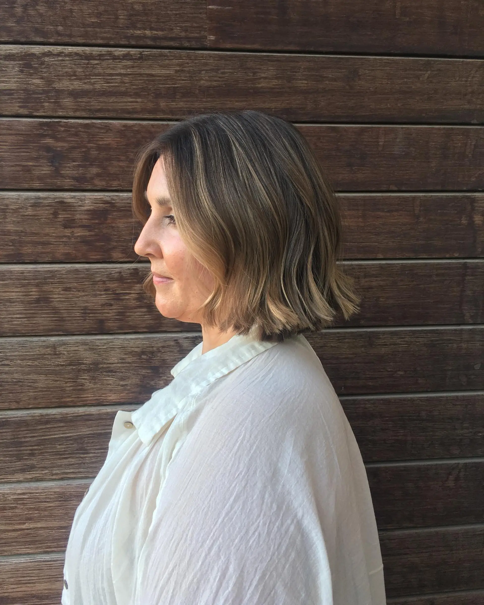 A chin-length textured bob with subtle wave styling and golden face-framing balayage highlights. 1