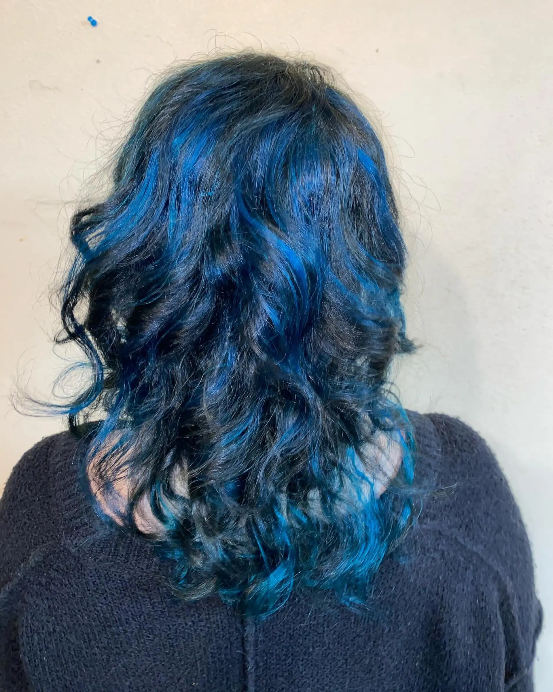 Medium-length wavy dark hair styled with vibrant, chunky electric blue highlights throughout. 1