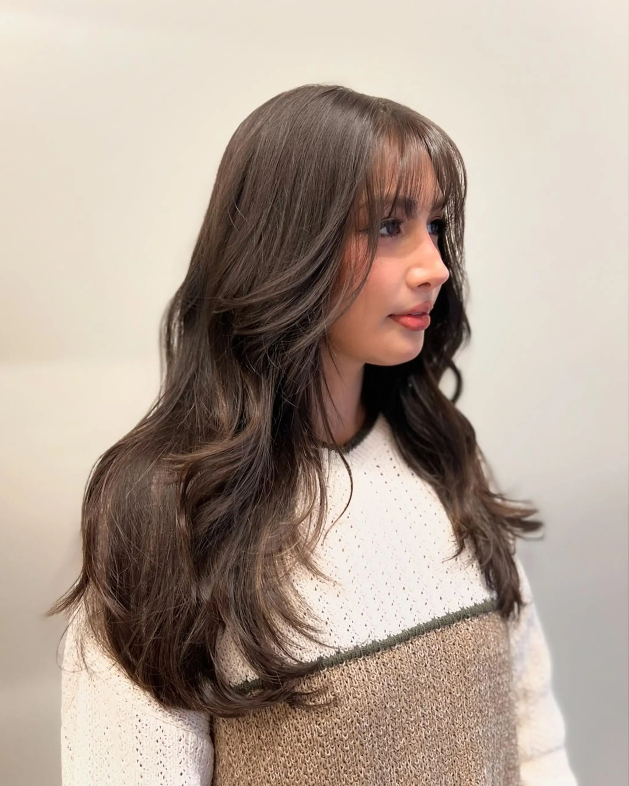 Long, dark brown wavy hair with soft waves, curtain bangs, and a side part.