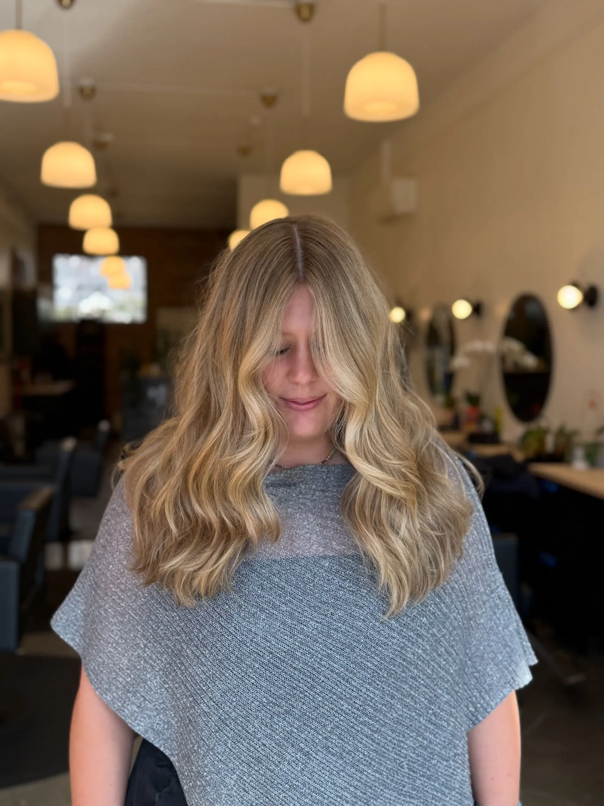 Long golden blonde hair styled in loose, lived-in waves with face-framing curtain layers. 1