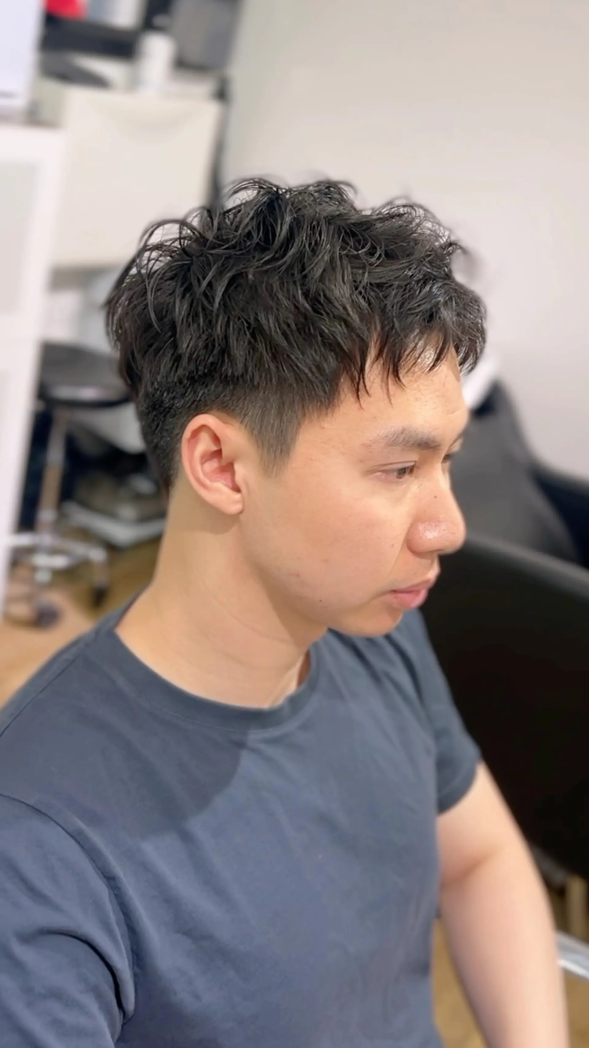 A short, textured cut enhanced with a soft pin-curl perm on top to create lived-in wave and movement, paired with neatly tapered sides. 1