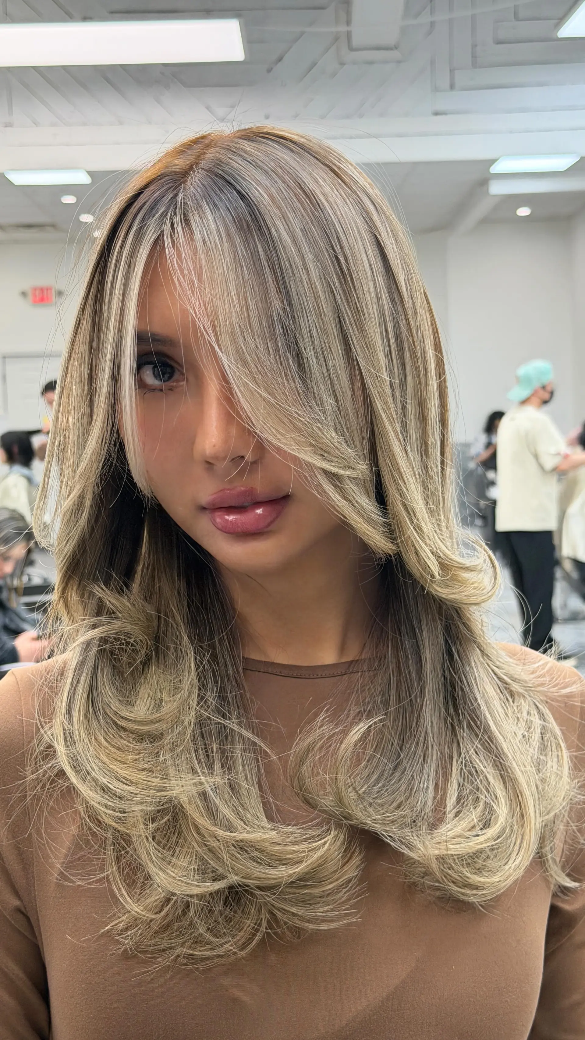 Long layered cool ash blonde hair styled in a smooth blowout with voluminous flipped ends and long face-framing fringe. 1