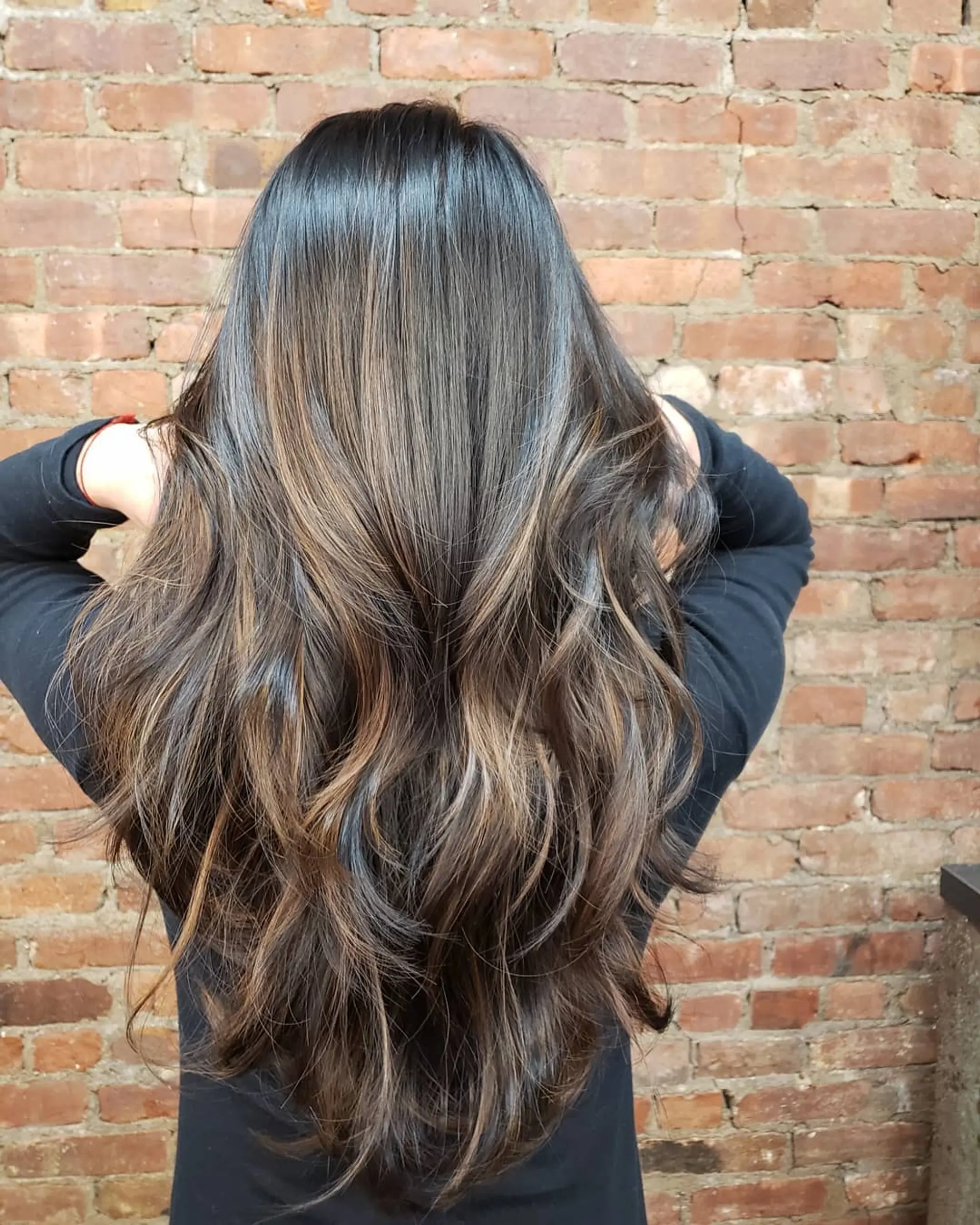 Long, flowing dark brown hair with subtle caramel balayage highlights and voluminous layered waves. 1