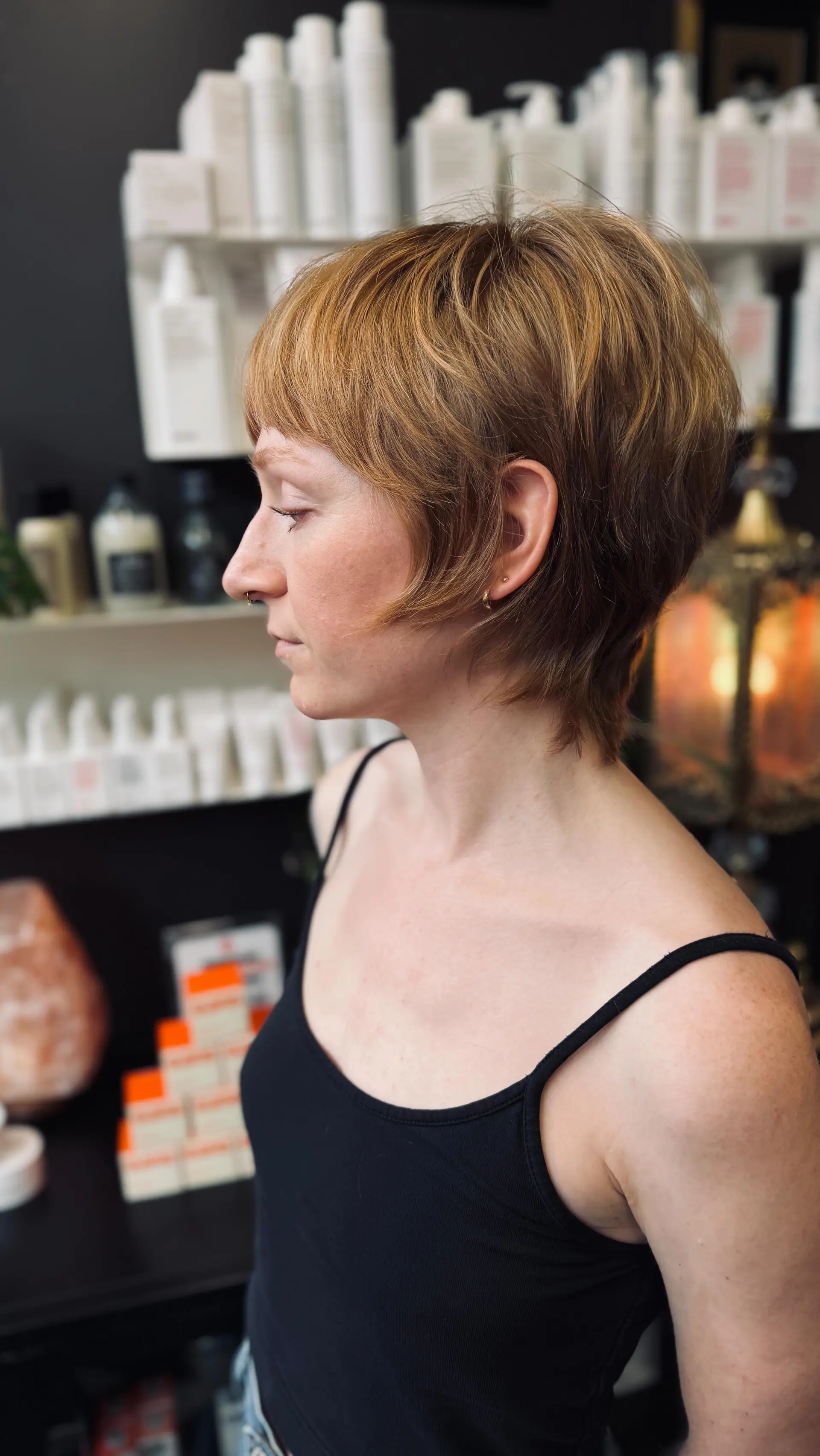 A razor-cut mixie cut with short textured layers, baby bangs, and wispy face-framing pieces around the ears and nape. 1
