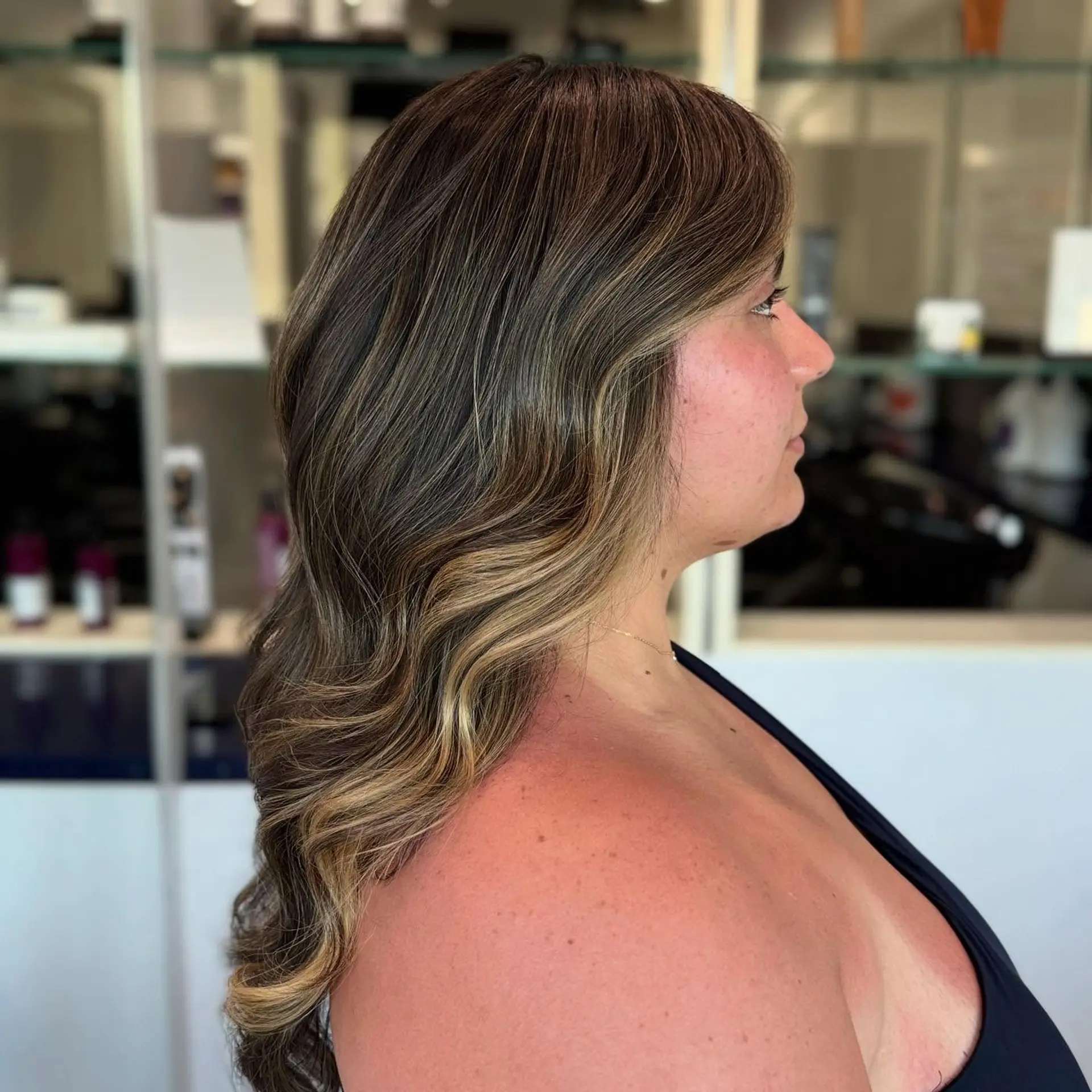 A medium-length wavy hairstyle with a bronzed blonde balayage. 1