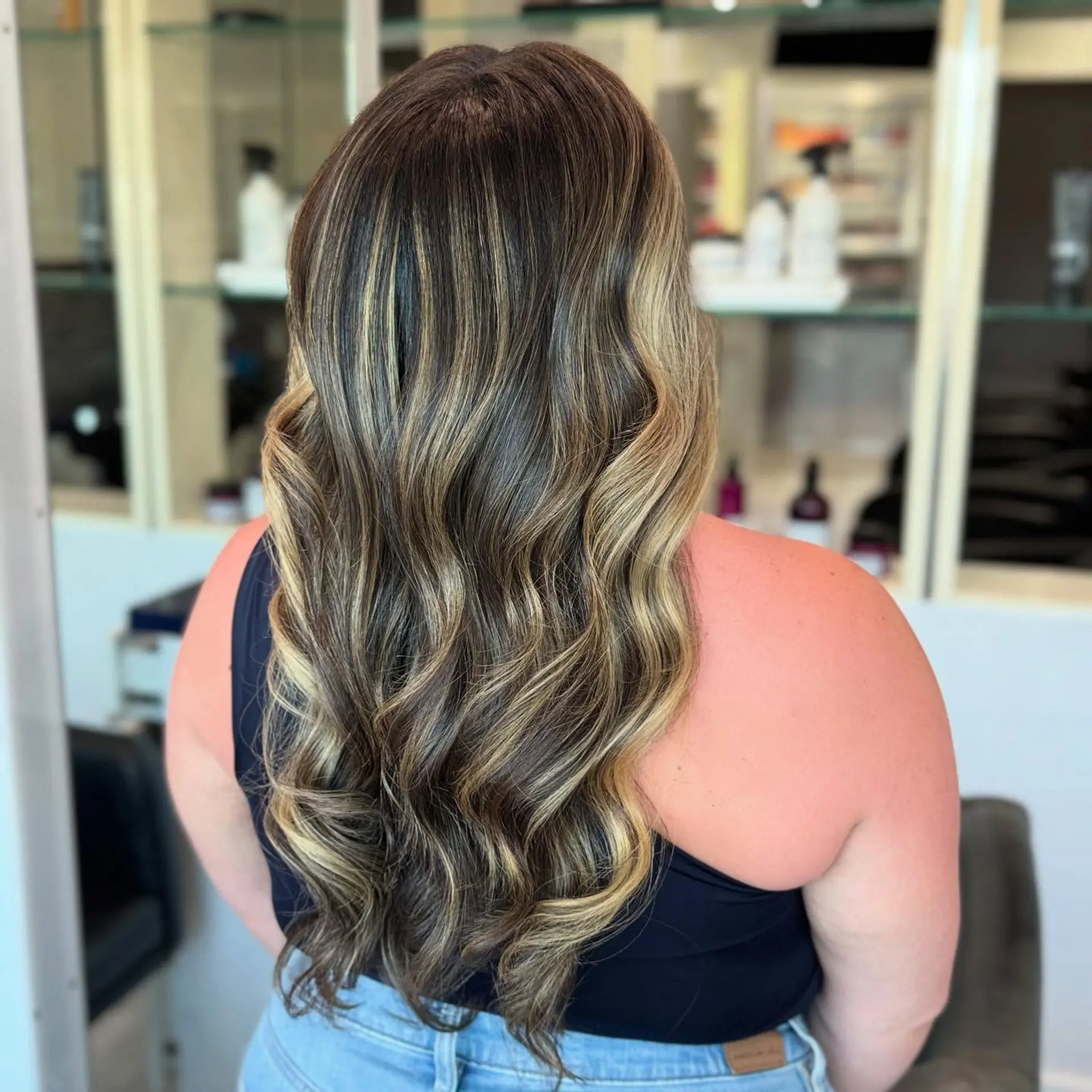 A medium-length wavy hairstyle with a bronzed blonde balayage. 2